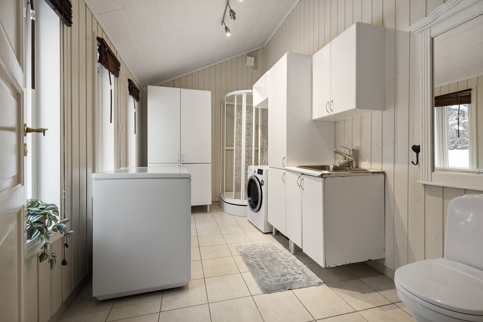 Praktisk vaskerom på 9 m² med flislagt gulv med elektriske varmekabler. Galleribilde