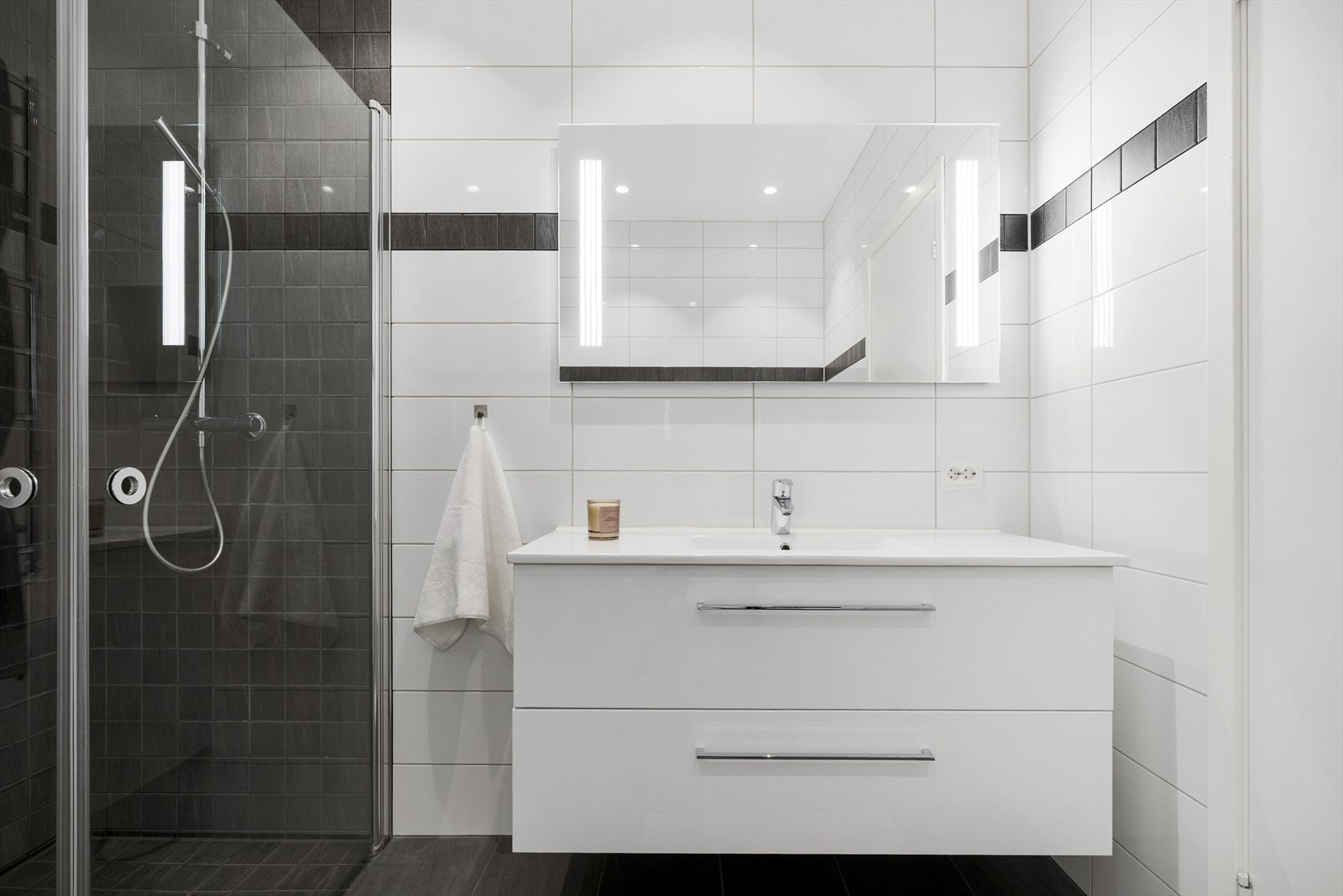 Dette baderommet kombinerer stilrene overflater med praktisk funksjonalitet. Galleribilde