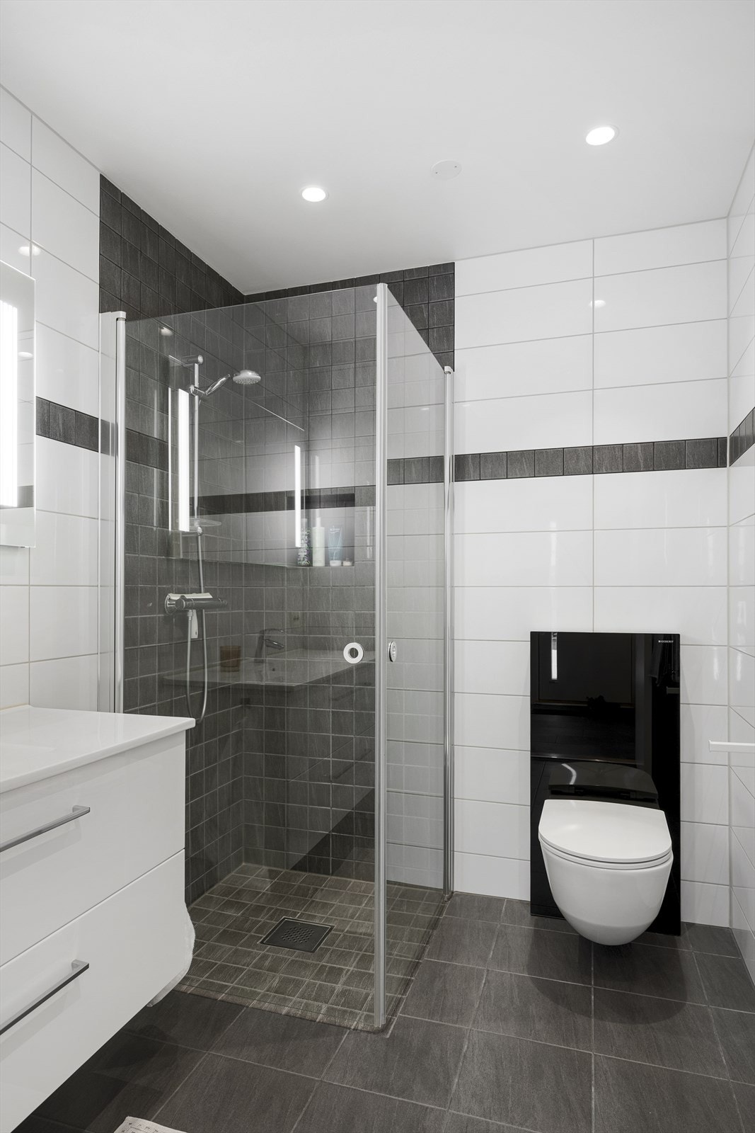 Her er det innredet med vegghengt toalett, servant med underskuffer, speil samt dusjhjørne med foldbare glassdører, en funksjonell og helhetlig løsning. Galleribilde