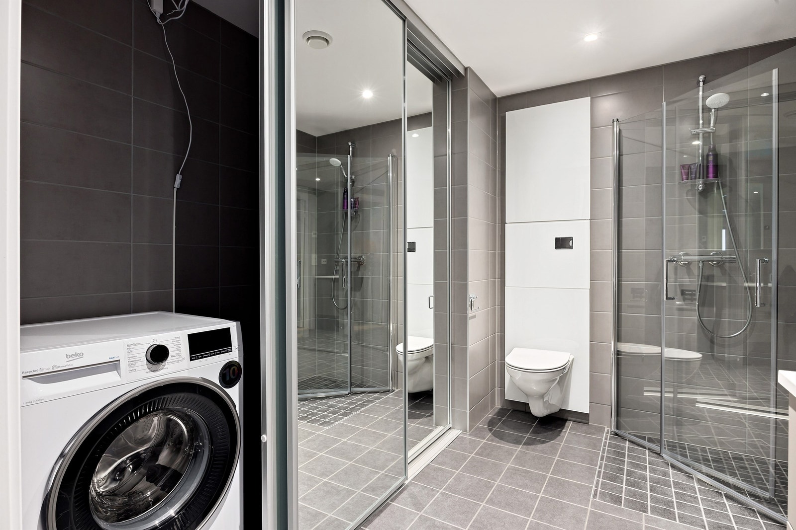 Skyvedører med speilfronter hvor vaskemaskin, tørketrommel og skittentøyskurv kan holdes skjult Galleribilde