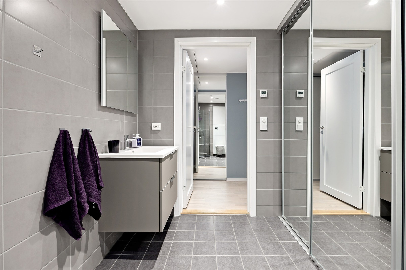 Badet inneholder veggmontert toalett med innbygget sisterne, stilrent servantskap med doble skuffer og dusjnisje Galleribilde