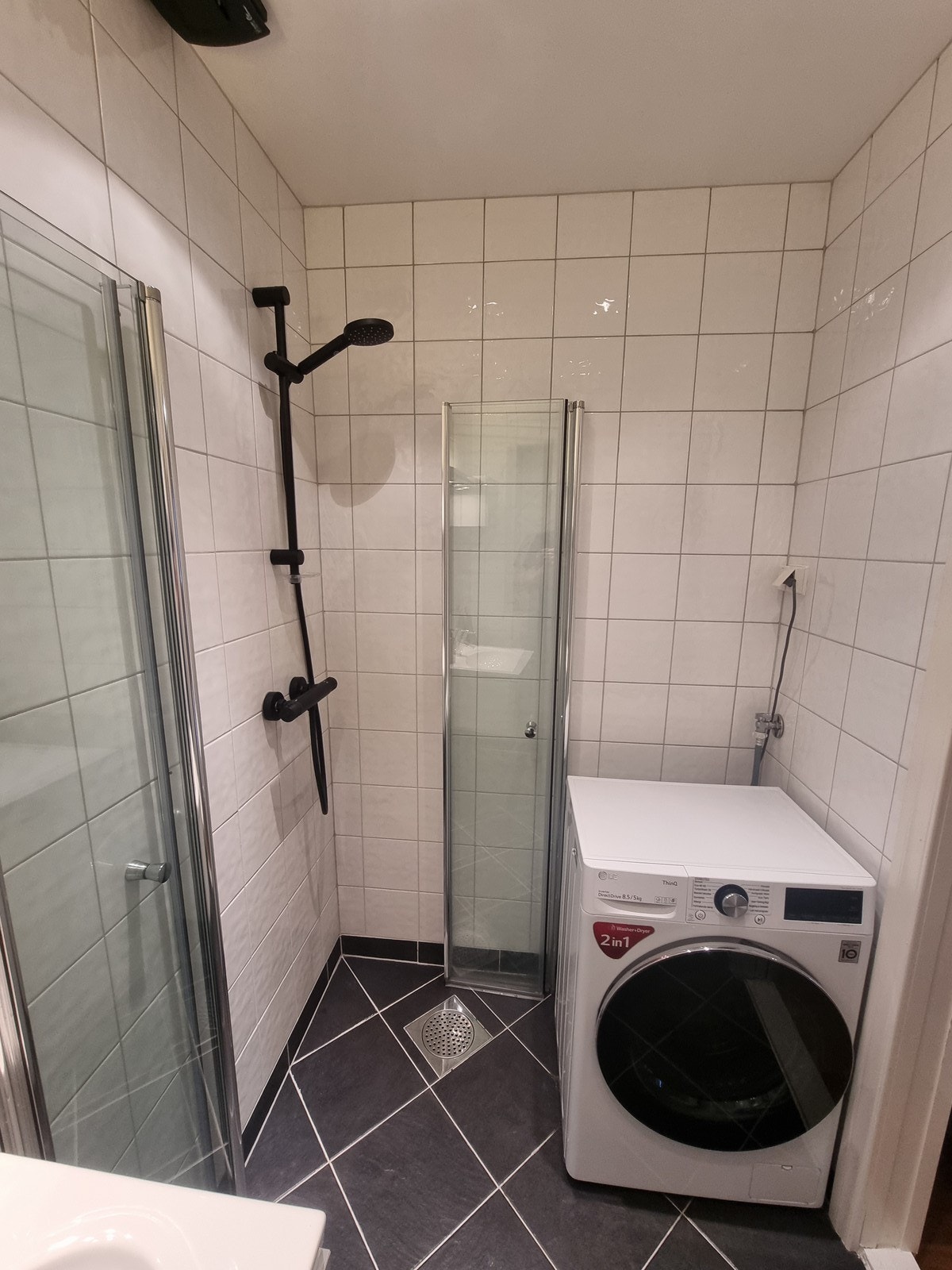 Badet er innredet med toalett, servant med oppbevaring, dusj og kombinert vask/tørketrommel Galleribilde