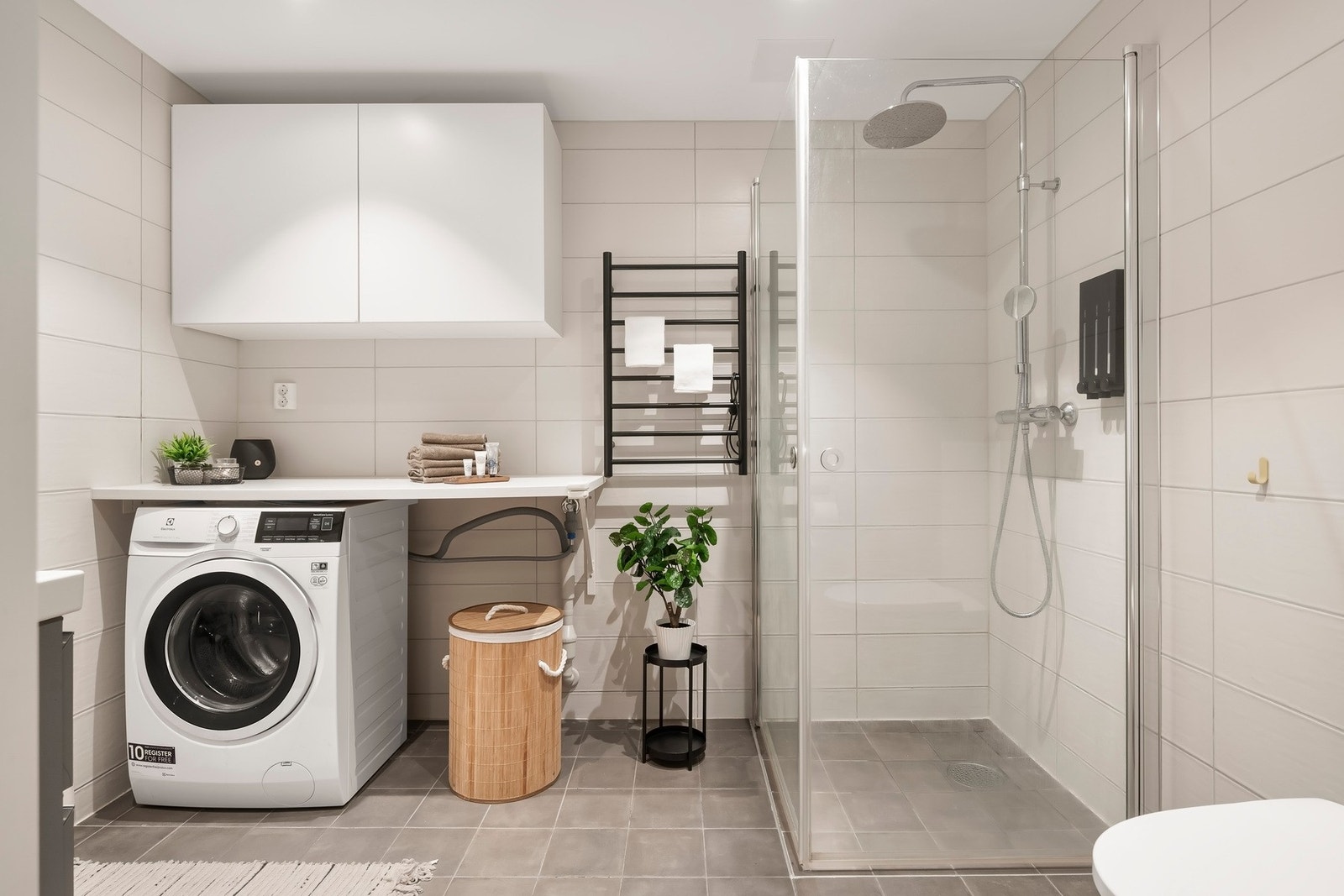 Delikat innredet baderom med dusjhjørne, servantløsning med underskap, vegghengt toalett, samt opplegg til vaskemaskin Galleribilde