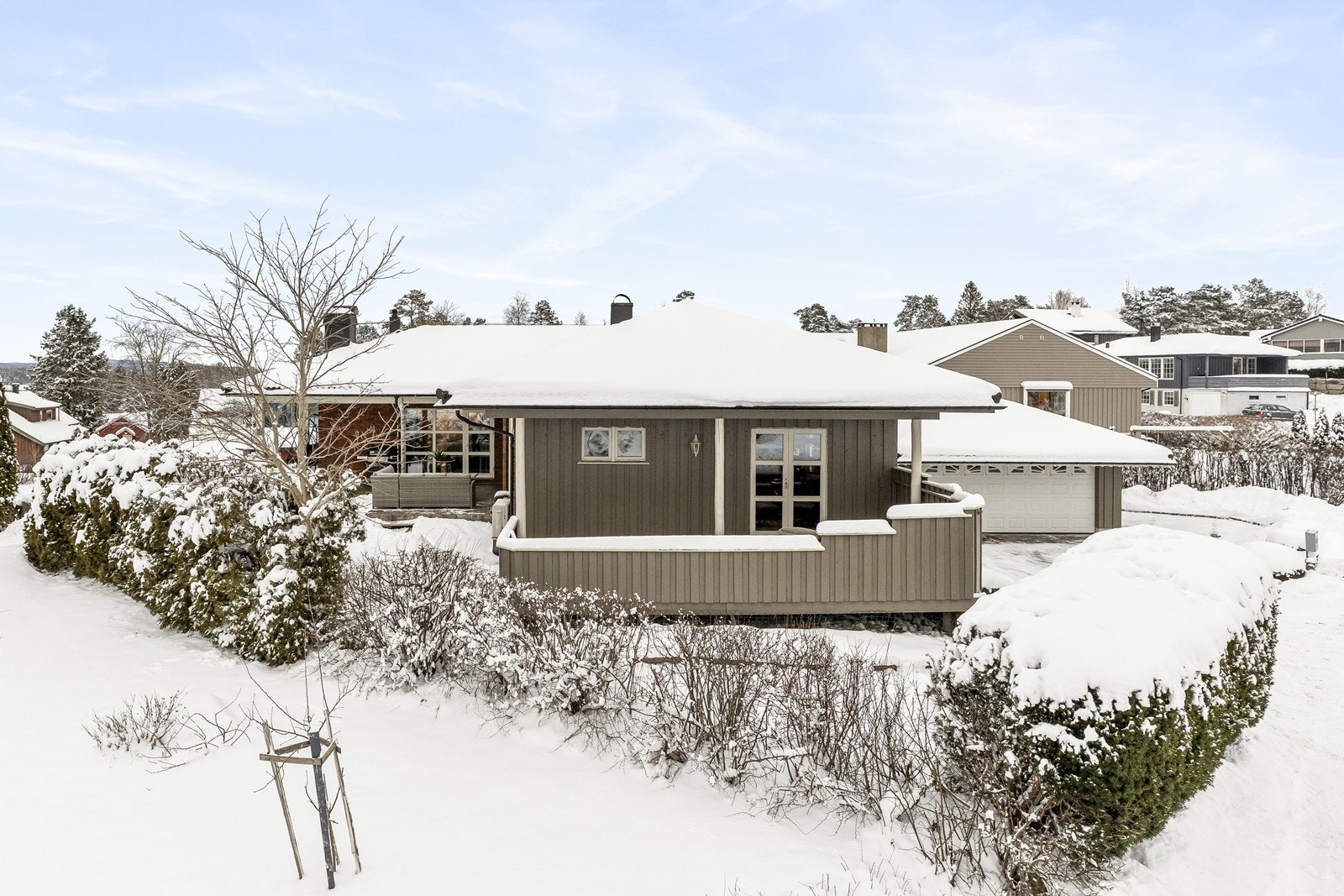 Eiendommen er omkranset av en hekk som gir privatliv og en grønn ramme. Galleribilde