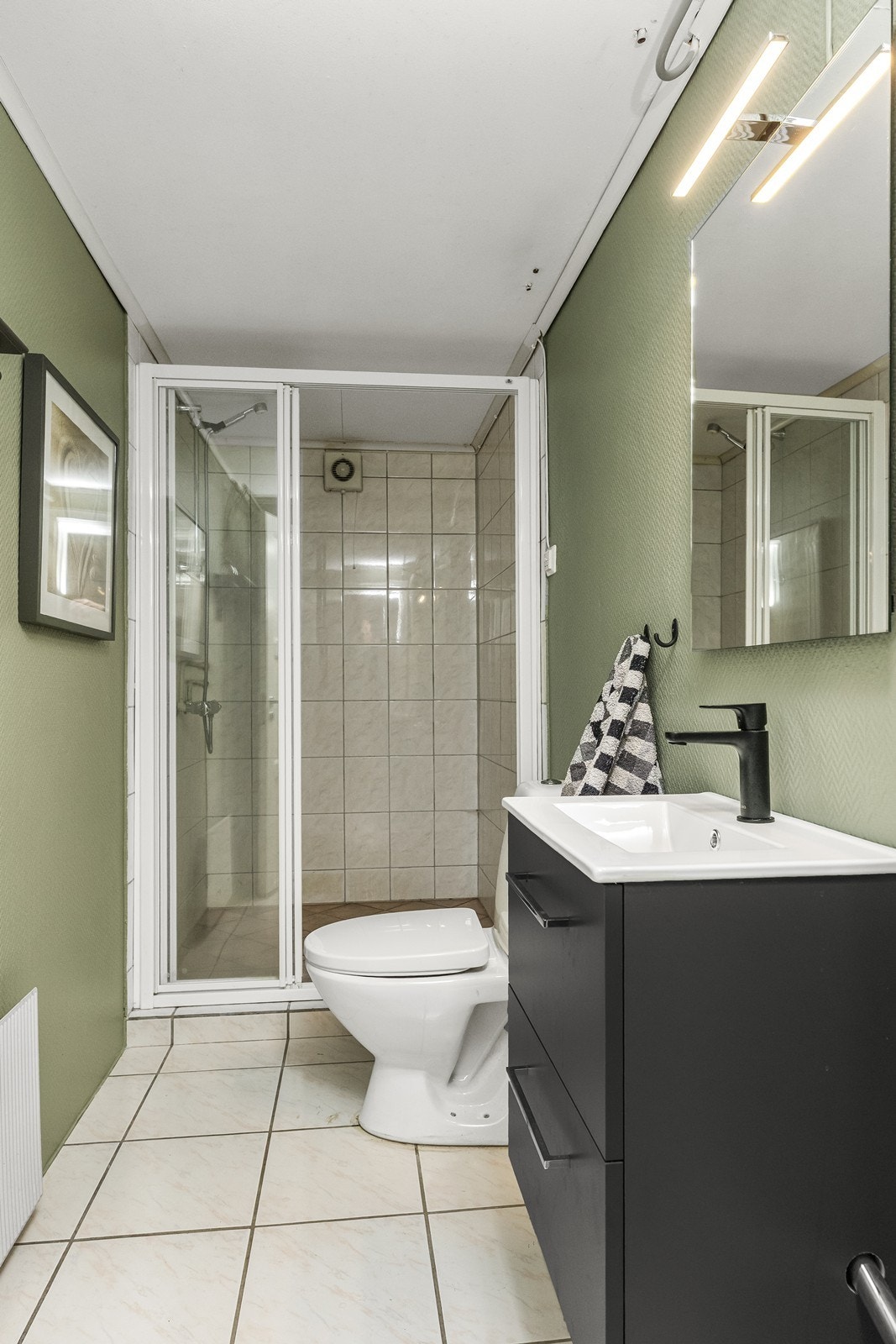 Praktisk bad i underetasjen med dusjkabinett, toalett og servant med skuffeseksjon. Galleribilde