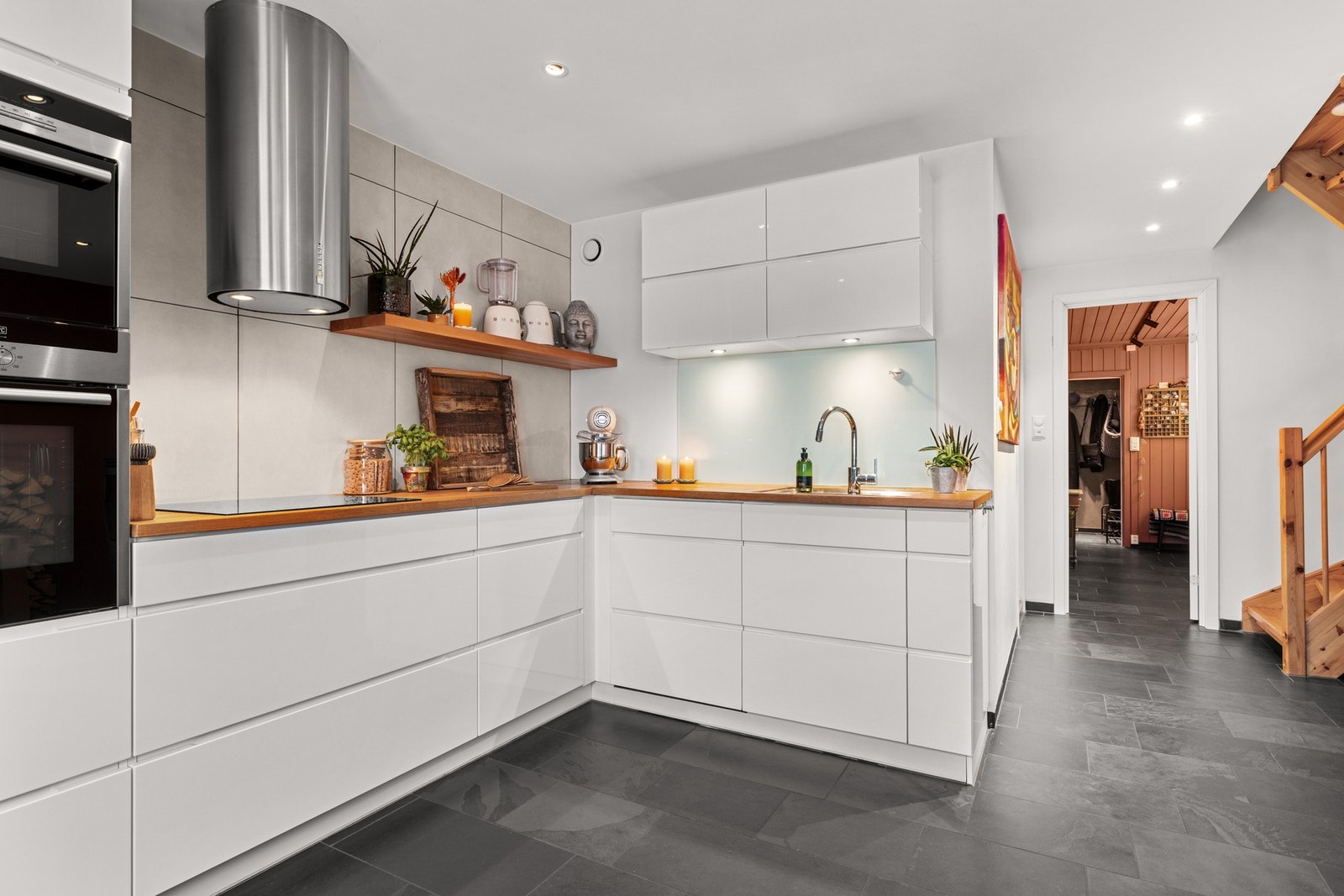 Kvik kjøkkeninnredning med glatte høyglans skapfronter. Innfelte hvitevarer som koketopp, stekeovn, oppvaskmaskin, kjøl/- fryseskap. Galleribilde