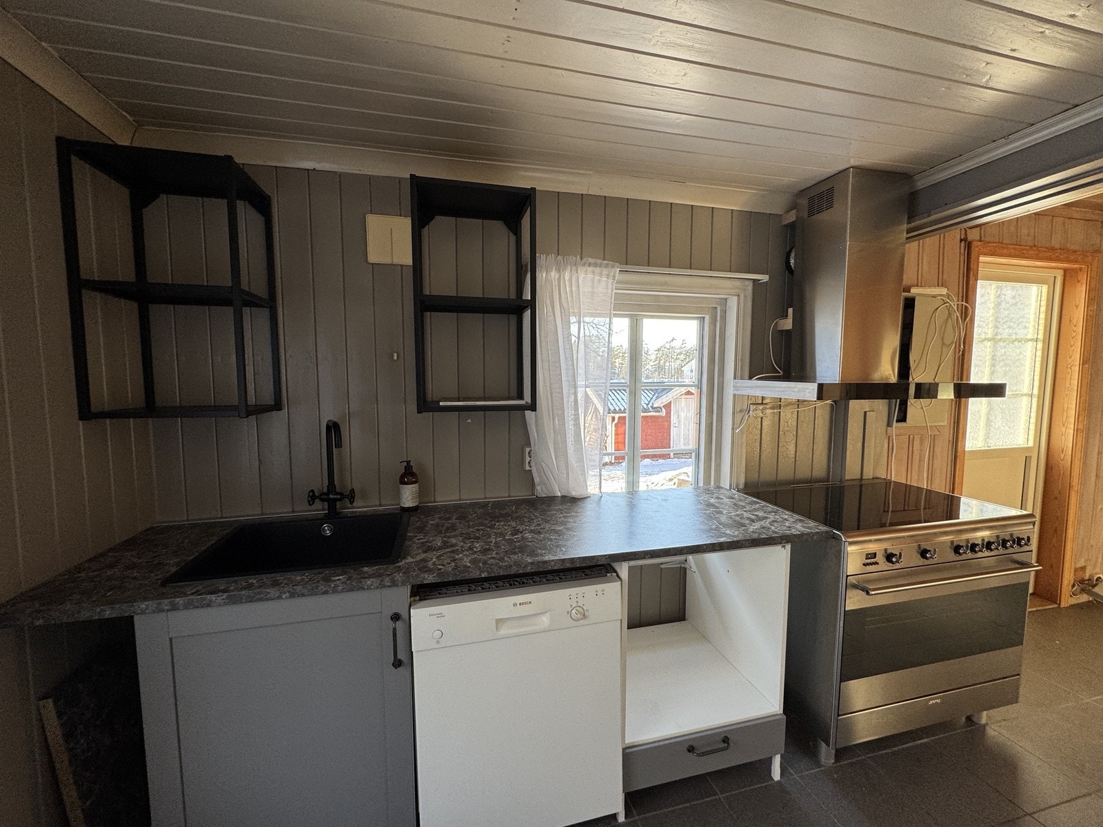 Kjøkken med oppvaskmaskin, komfyr og opplegg for vaskemaskin. Galleribilde