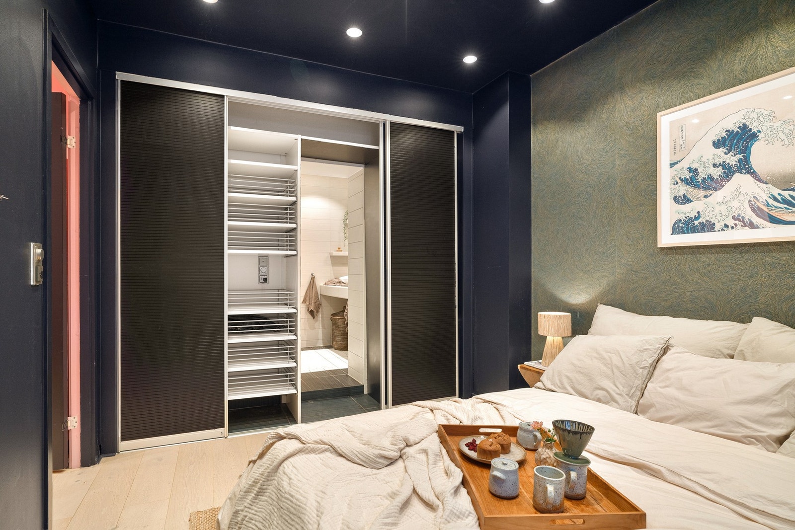 Plasstilpasset skyvedørsgarderobe med oppbevaringsmuligheter, og med skjult adkomst til badet. Galleribilde