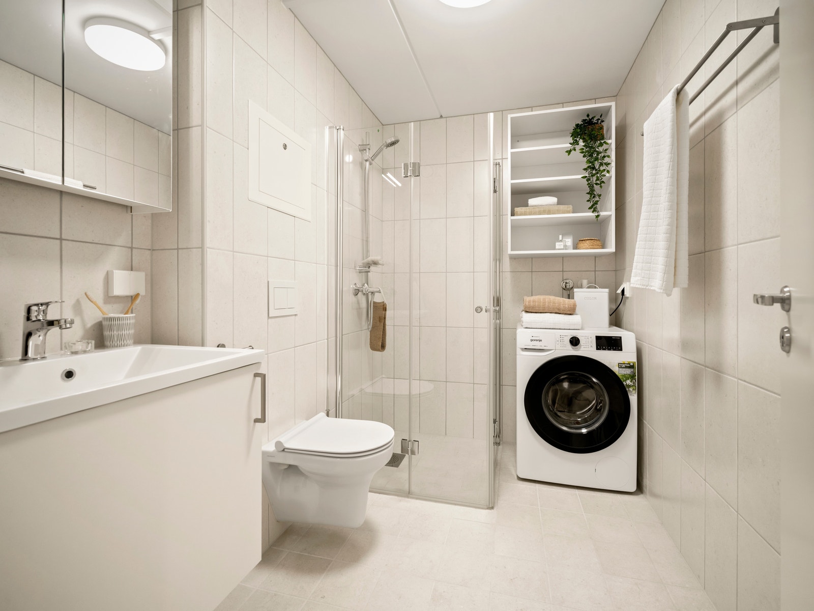 Flislagt bad med vaskemaskin, moderne innredning og praktiske hyller. Gir en ekte spa-følelse hjemme. Galleribilde