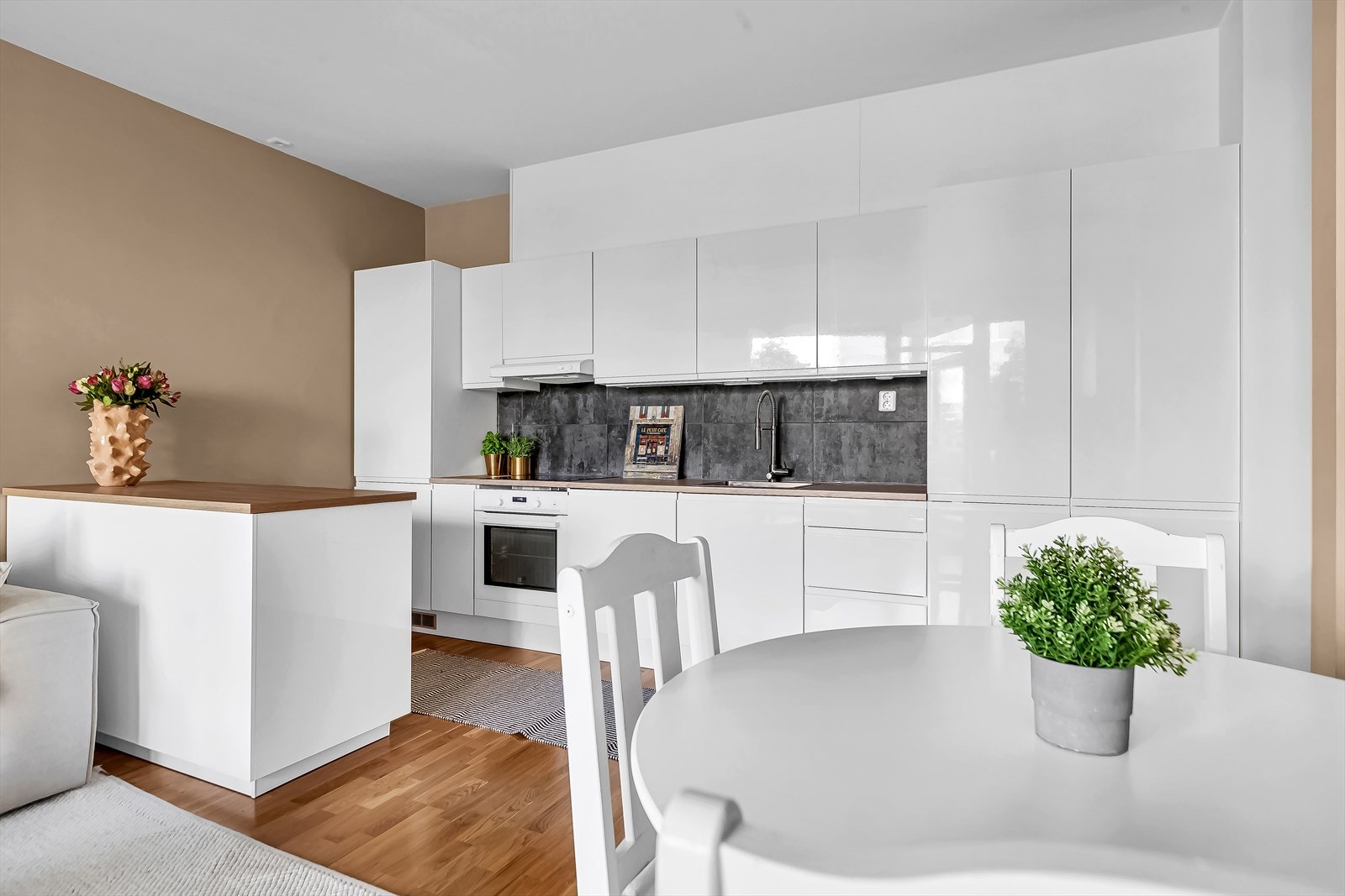 Stilrent kjøkken med en flott kjøkkenøy. Kjøkkenet har gode arbeidsflater og rikelig med skapplass Galleribilde