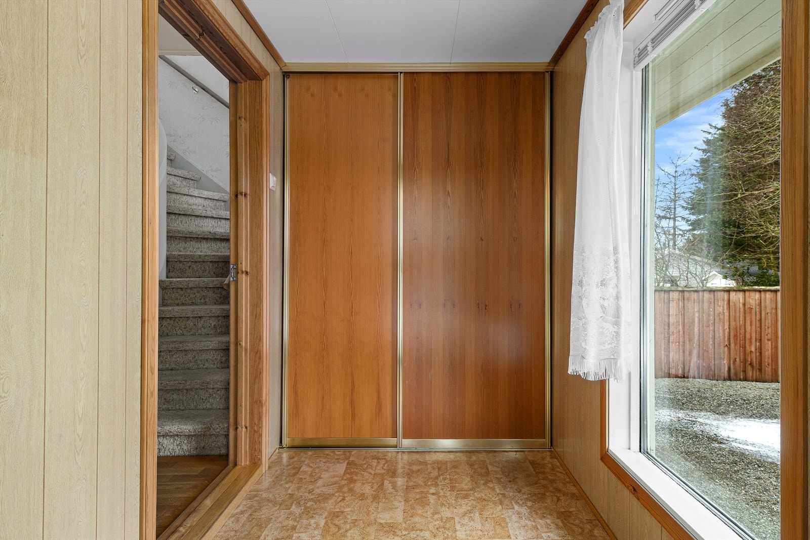 Romslig gang med skyvedørsgarderobe og stort vindu som slipper inn mye lys i boligen. Galleribilde