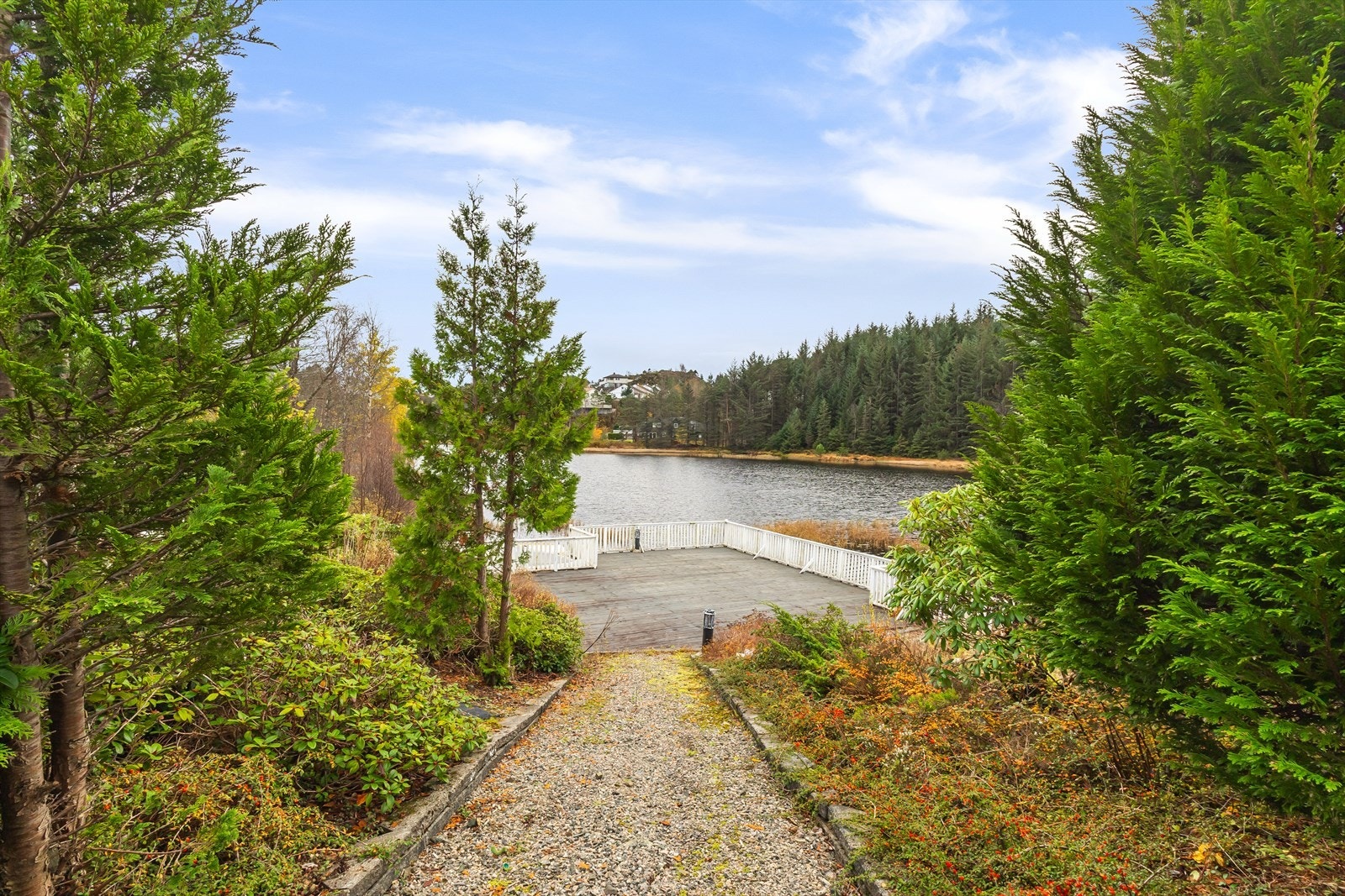 Gruslagt sti leder ned til en stor trebrygge ved vannet. Galleribilde