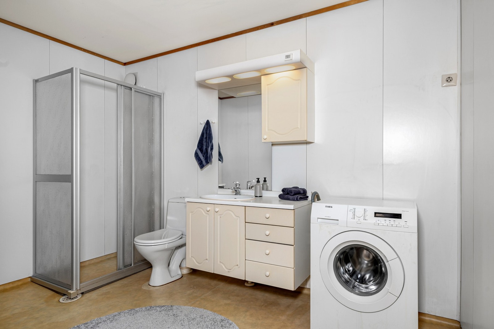 Bad med dusjhjørne, wc, innredning med speil og opplegg for vaskemaskin. Galleribilde