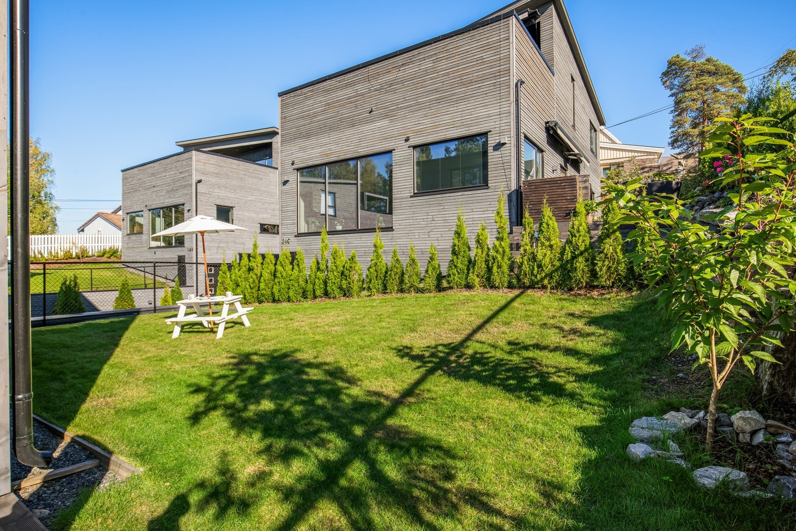 Hagen er delvis inngjerdet, og er pent opparbeidet med gressplen og tujahekker Galleribilde