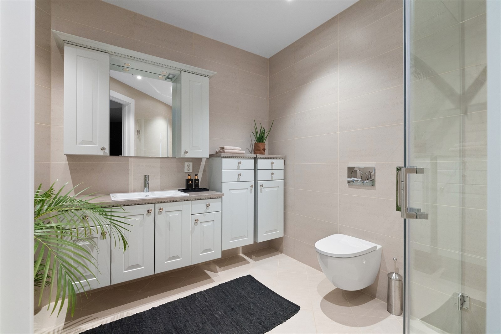 Badet er lyst og lekkert innredet med dusjhjørne og omfangsrik baderomsinnredning. Galleribilde