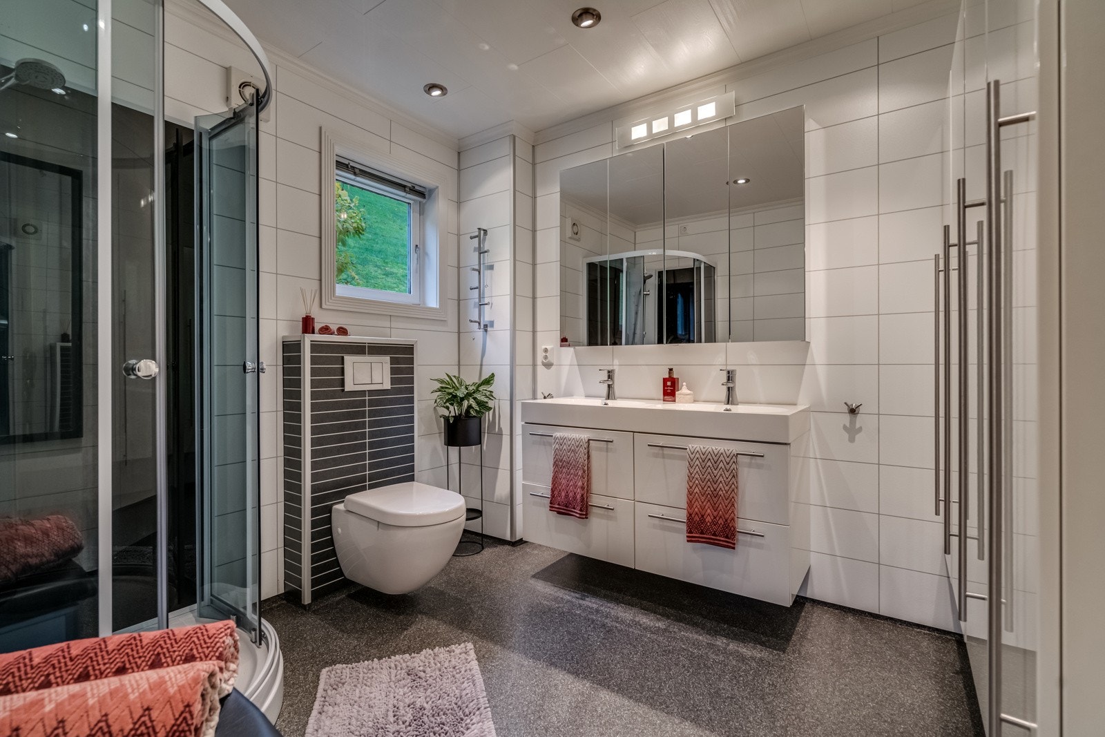 Badet som har belegg på gulv og baderomsplater på vegger. Her er det dusj, servant og wc. Galleribilde