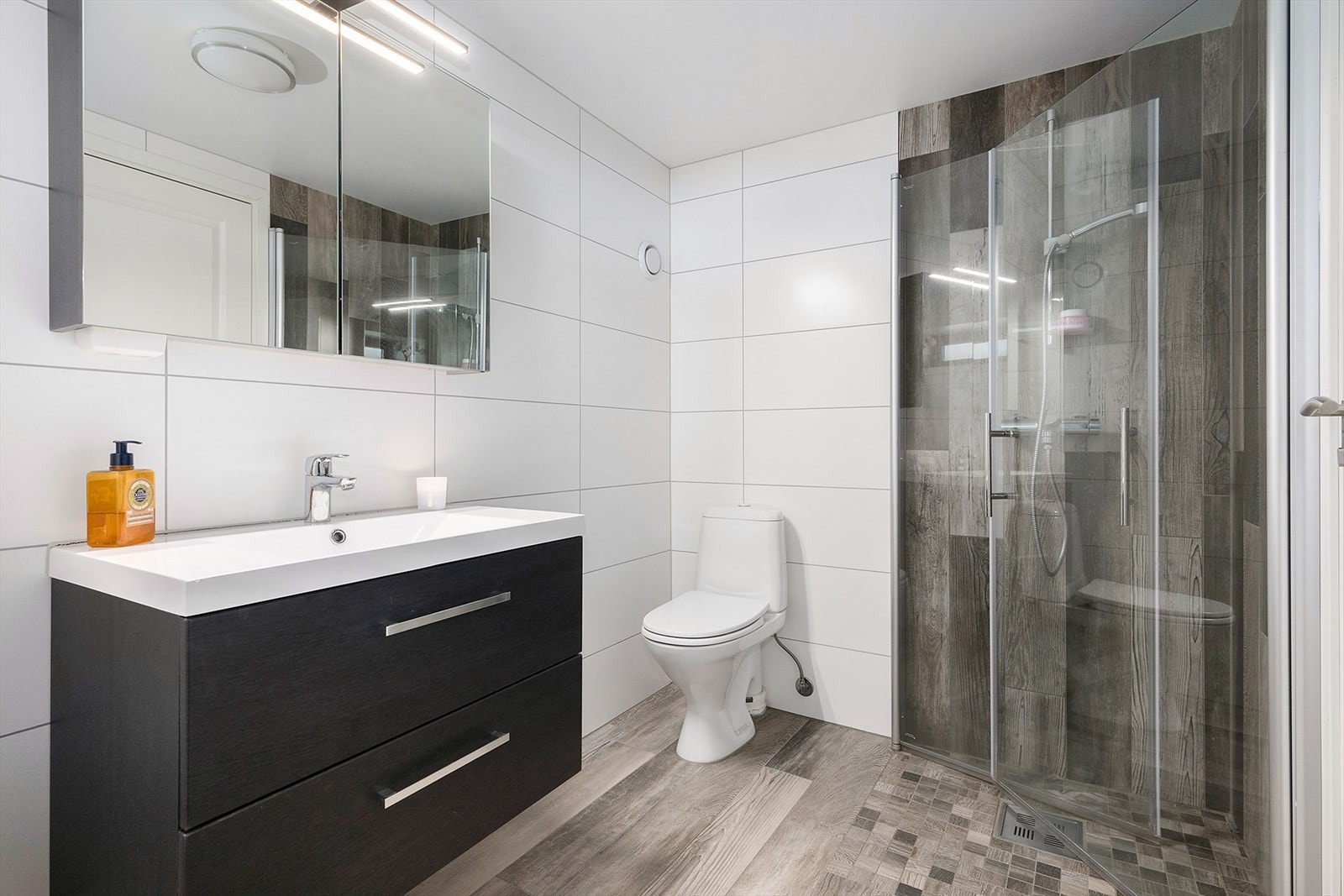 Pent, moderne bad fra 2019 med gulvvarme og mekanisk avtrekk. Badet er utstyrt med toalett, dusjplass med inn-utadslående dusjvegger, speilskap og servant med ettgreps blandebatteri i innredning. Galleribilde