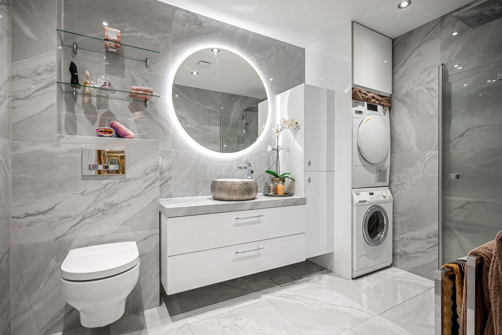 Bak en halvvegg er det praktisk vaskesone med opplegg for vaskemaskin og tørketrommel i søyleløsning. Galleribilde