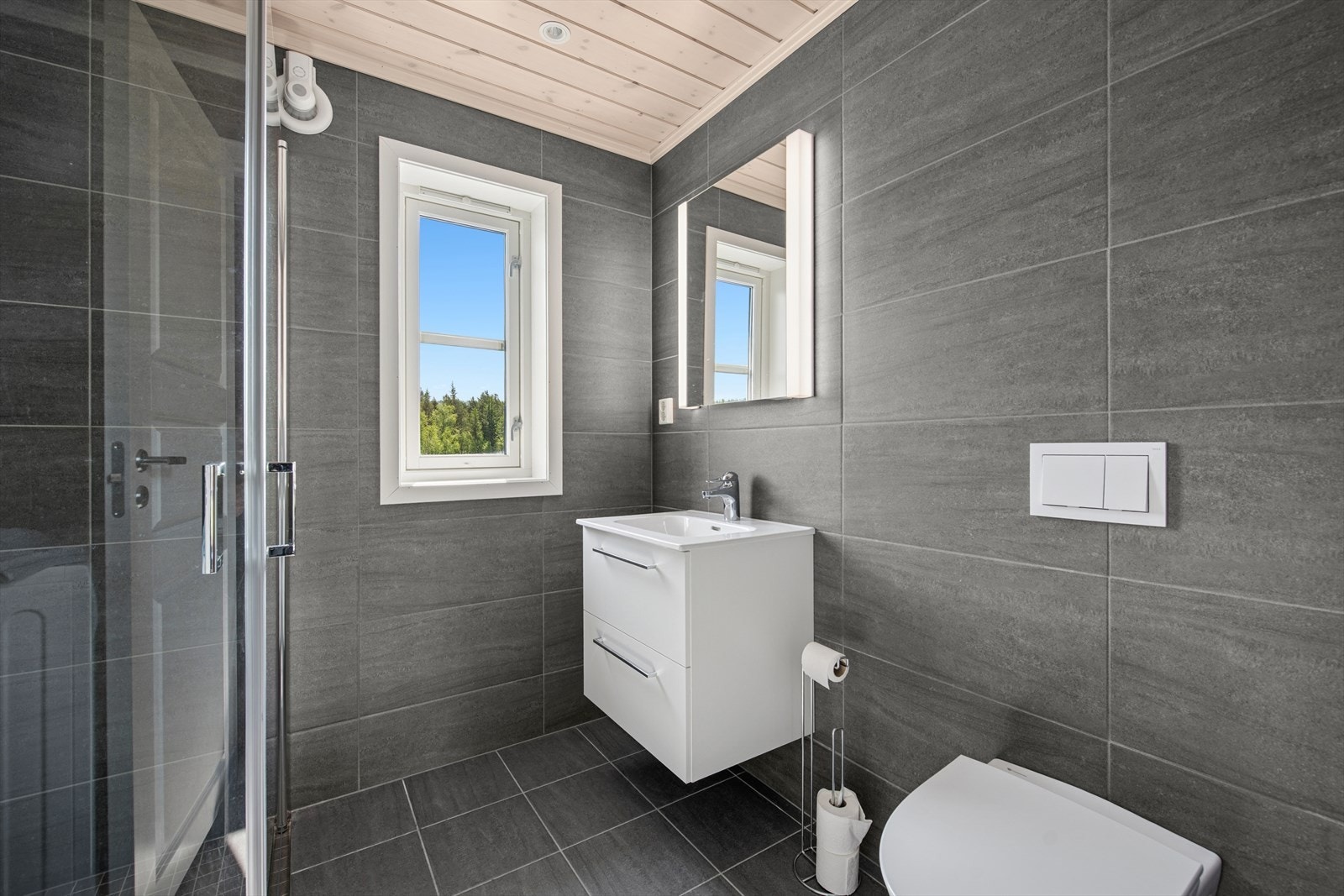 Innredning med glatte fronter, helstøpt servant, oppbevaring i skuffeseksjon og speil med belysning. Galleribilde