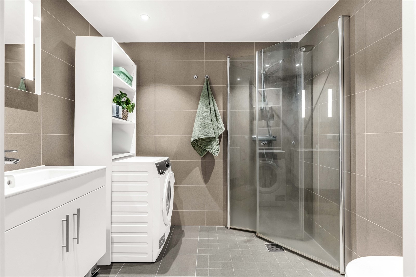 Baderommet har flislagte overflater med elektrisk gulvvarme. Innredningen består av servantskap med nedfelt servant, underskuffer og 1-greps blandebatteri. Videre er det satt inn dusjhjørne med glassdører, opplegg for vaskemaskin og vegghengt toalett. Galleribilde