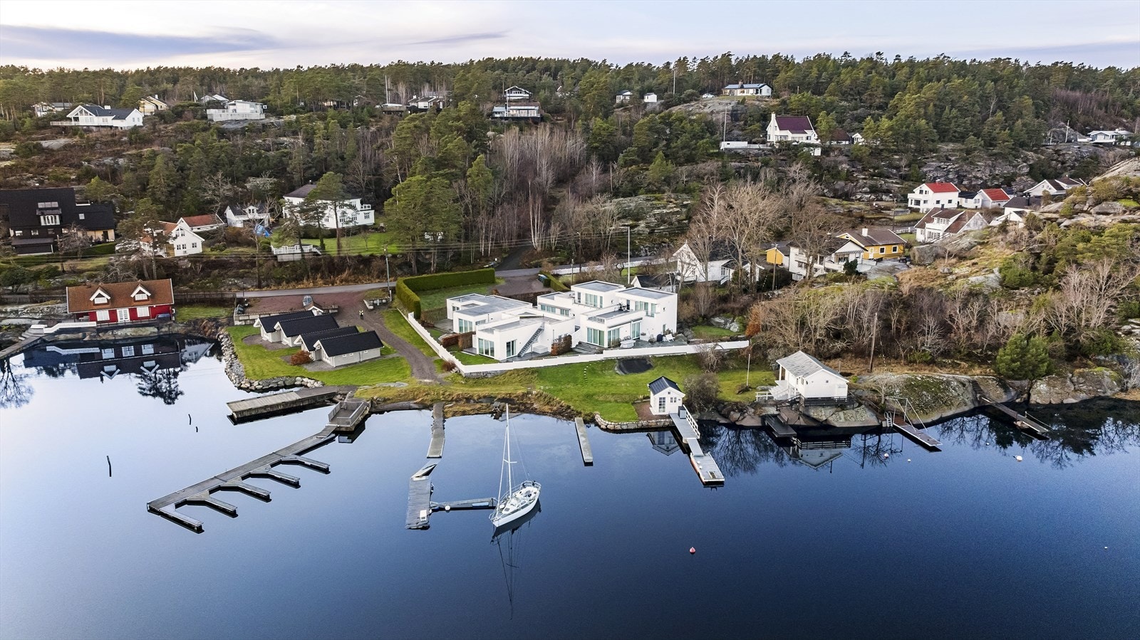 Eiendommen er pent opparbeidet med gressplen, og steinheller som leder videre mot naboeiendommen. Tomtegrensene er tydelig markert med grensepæler. Galleribilde