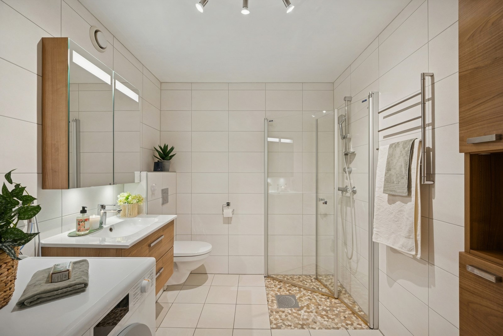 Delikat baderom fra 2012 med flislagte overflater og varmekabler i gulv. Innredet med vegghengt toalett, dusj med innfellbare dører og servant med servantskap, samt speil og skap med belysning. Galleribilde