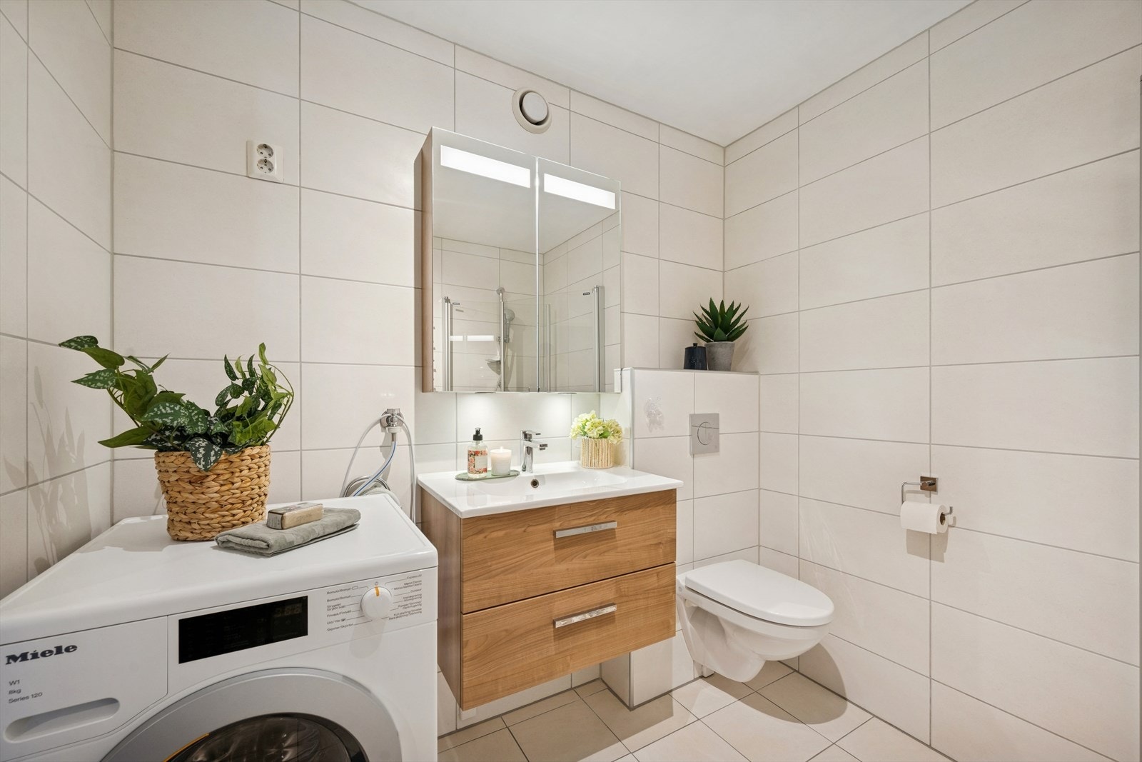 Praktisk løsning med et stilrent og moderne preg. Baderommet har opplegg for vaskemaskin, som også følger med leiligheten. Galleribilde
