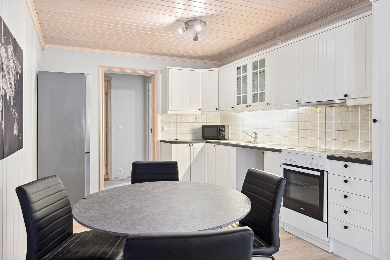 Pent kjøkken i hvite fronter. Hvitevarer: kombiskap, komfyr og oppvaskmaskin er satt inn. Galleribilde