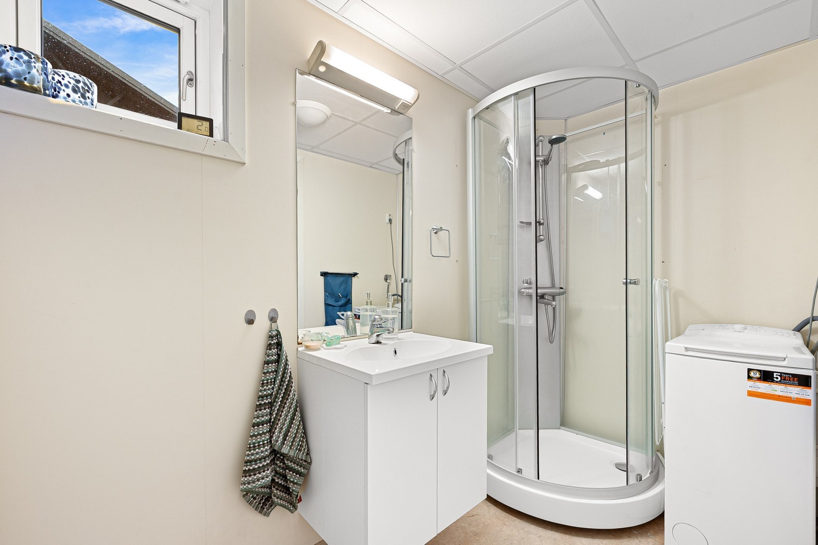 Badet er praktisk utstyrt med dusjkabinett, servant, opplegg for vaskemaskin og gulvmontert WC. Galleribilde