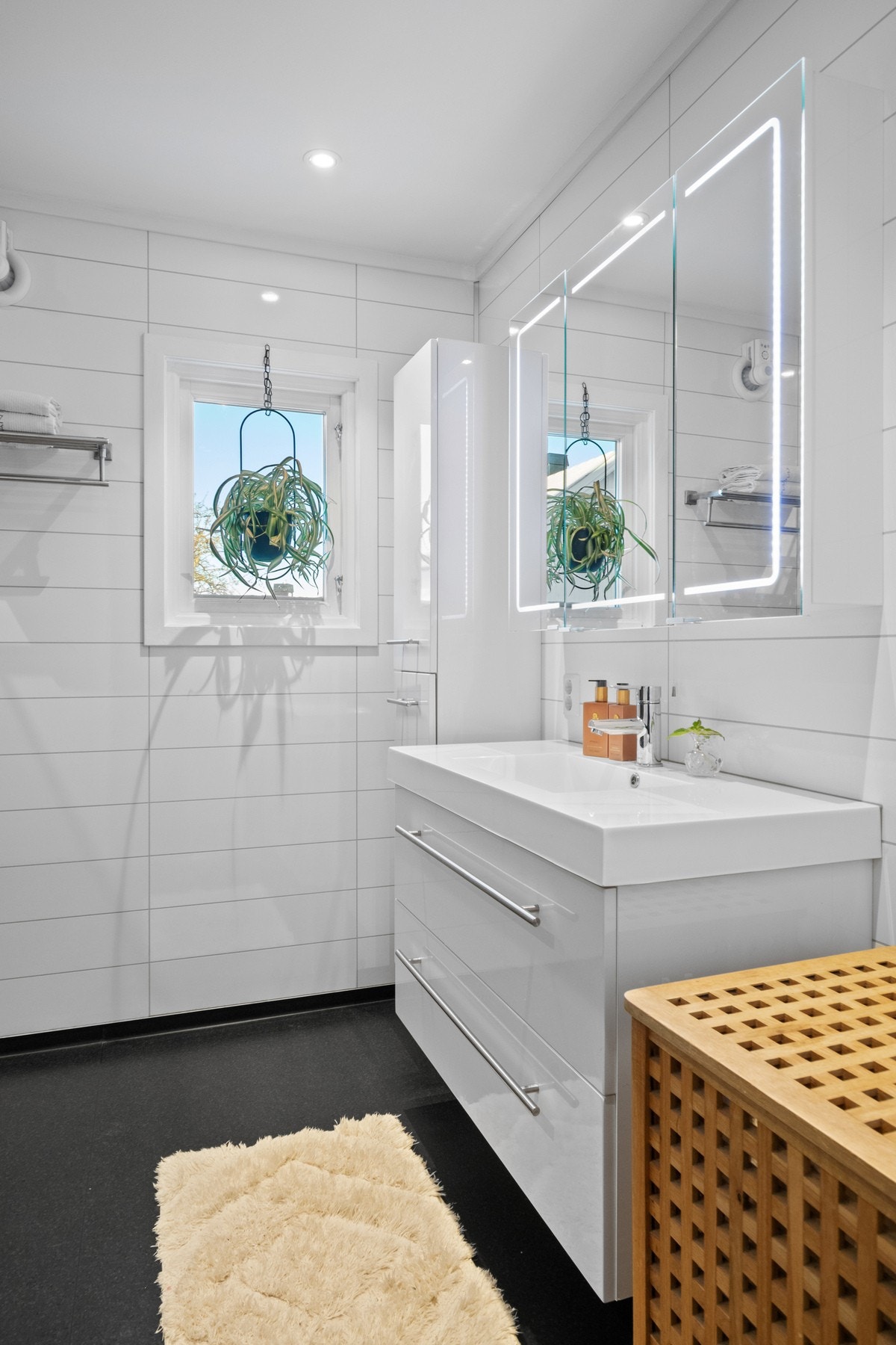 Innredningen består av servant med hvite skuffer, et matchende høyskap samt et stilrent speilskap med integrert belysning. Galleribilde