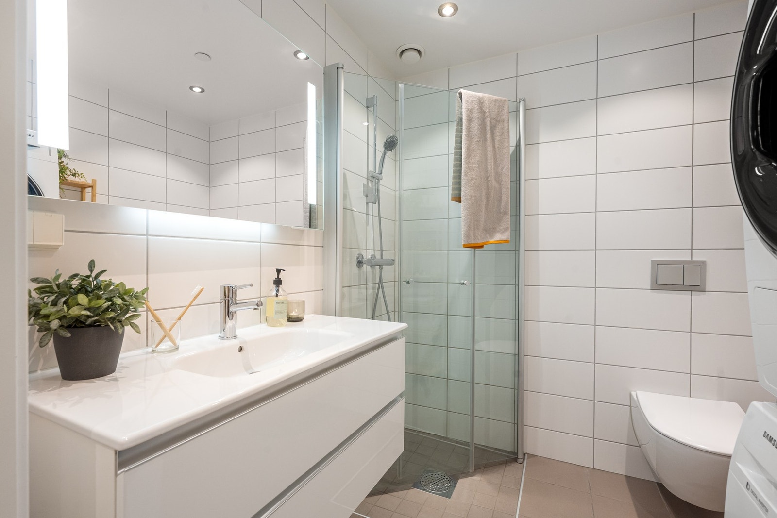 Flott baderom fra 2017 (byggeår) med vegghengt toalett, dusj, servant og opplegg for vaskemaskin. Galleribilde