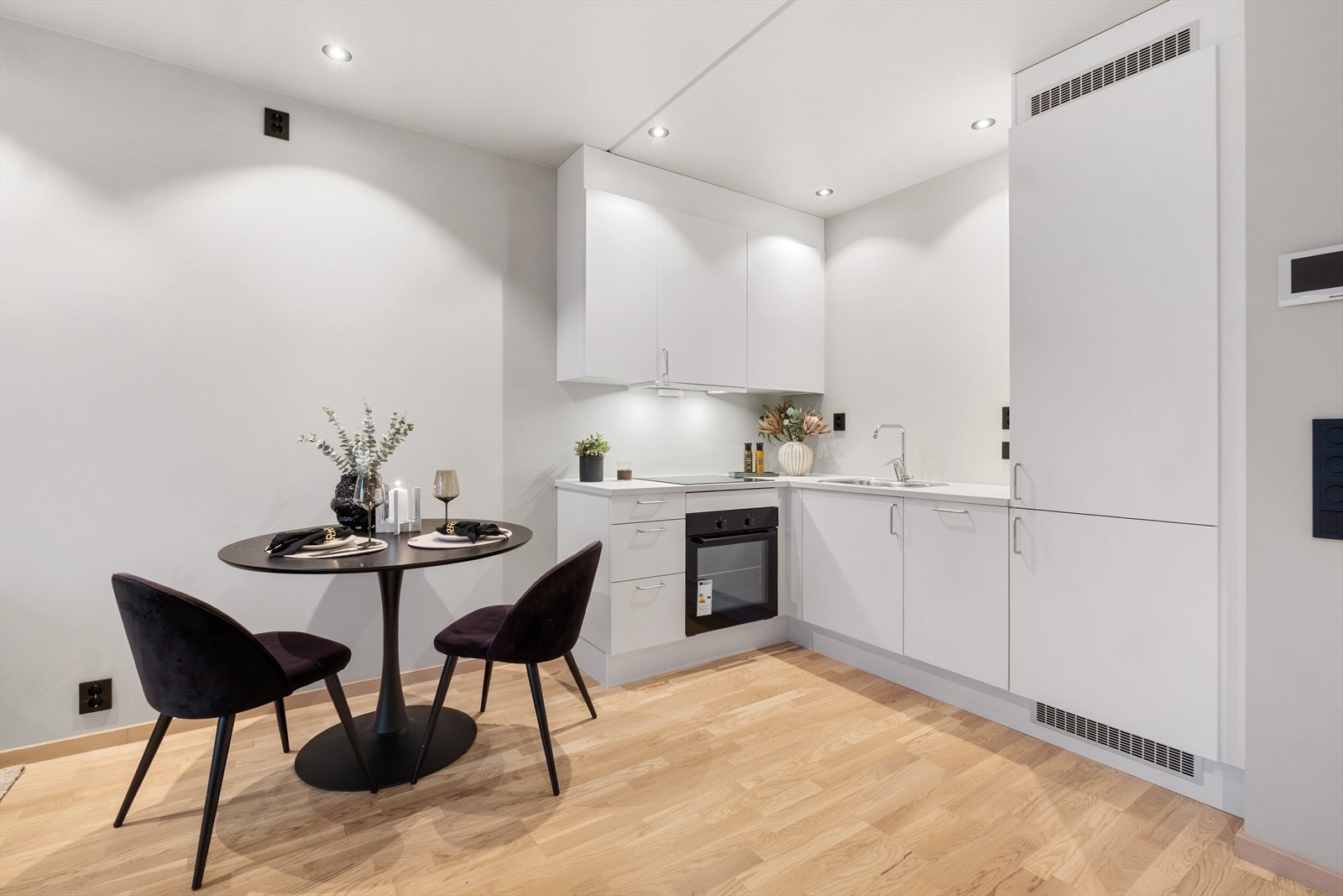 Kjøkkenet har en moderne utforming med hvit kjøkkeninnredning i glatt høytrykkslaminat og takhøye overskap som gir gode oppbevaringsmuligheter Galleribilde