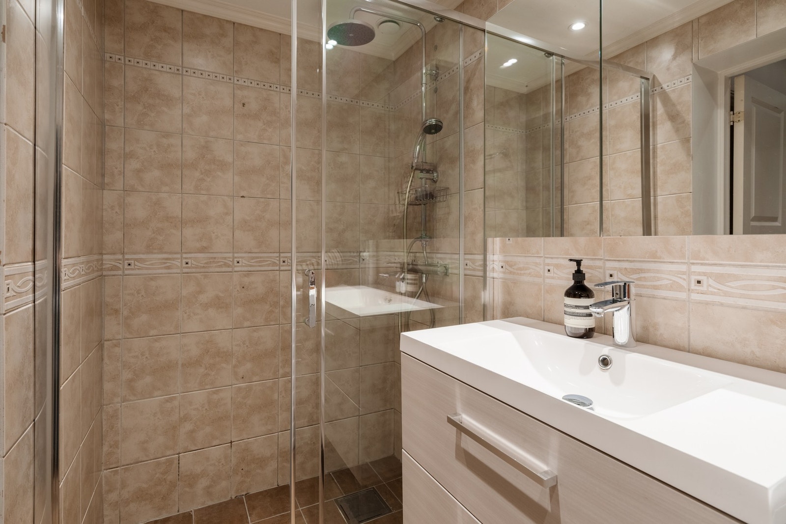 Moderne baderomsinnredning med heldekkende servant med servantskuffer og vegghengt speilskap. Galleribilde