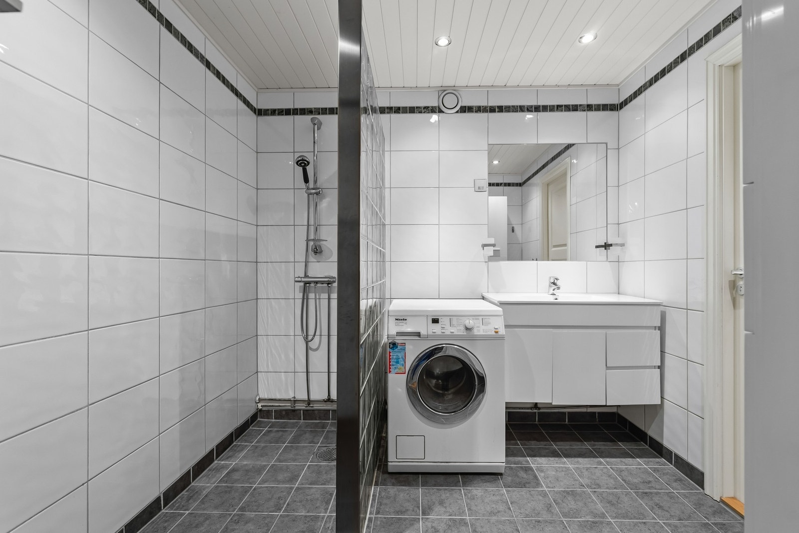 Bad med varme i gulvet. Baderomsinnredning med benkeskap og veggskap med glatte fronter. Galleribilde