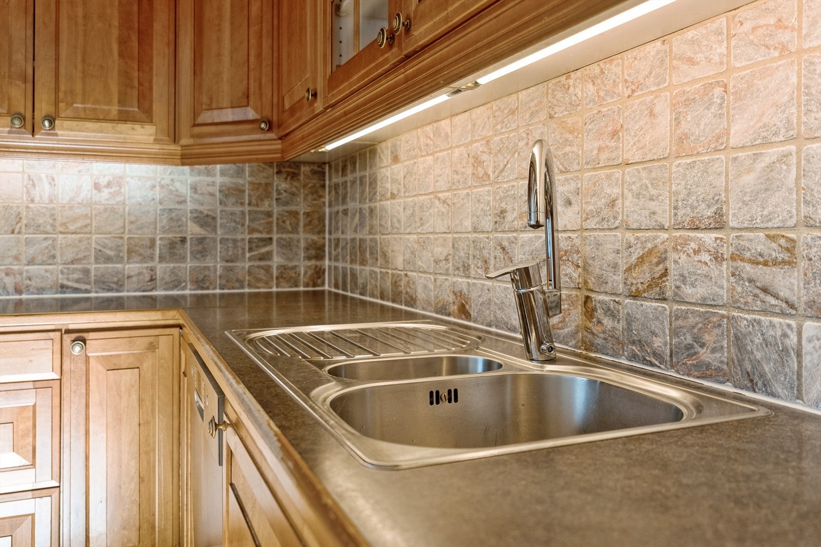 Det er laminat benkeplate og flis mellom benk og overskap Galleribilde