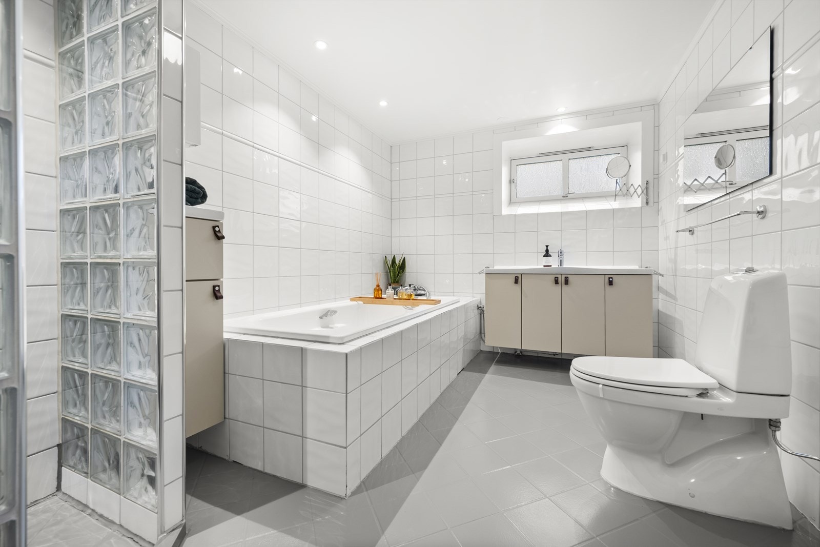 Badet er praktisk innredet med klosett, servant på innredning, badekar og et eget dusjhjørne, som gir fleksible bruksområder for både avslapning og hverdagsbruk. Galleribilde