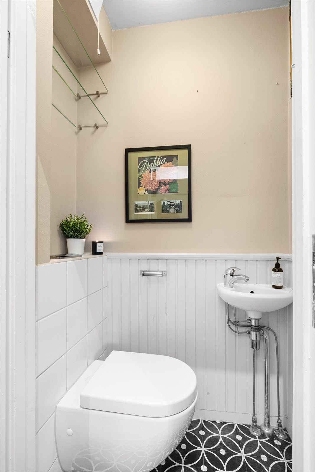 Et lite og praktisk toalettrom like innenfor inngangsdøren i 1. etasje. Rommet har malte plater i himling og på vegger, kombinert med trepanel som gir en fin materialvariasjon. Flislagt gulv, vegghengt toalett og servant med innredning. Galleribilde