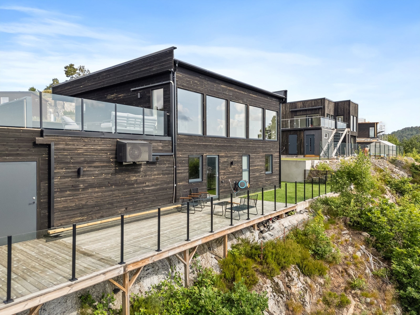 Flott uteplass med litt plen, terrasser og glassrekkverk. Galleribilde