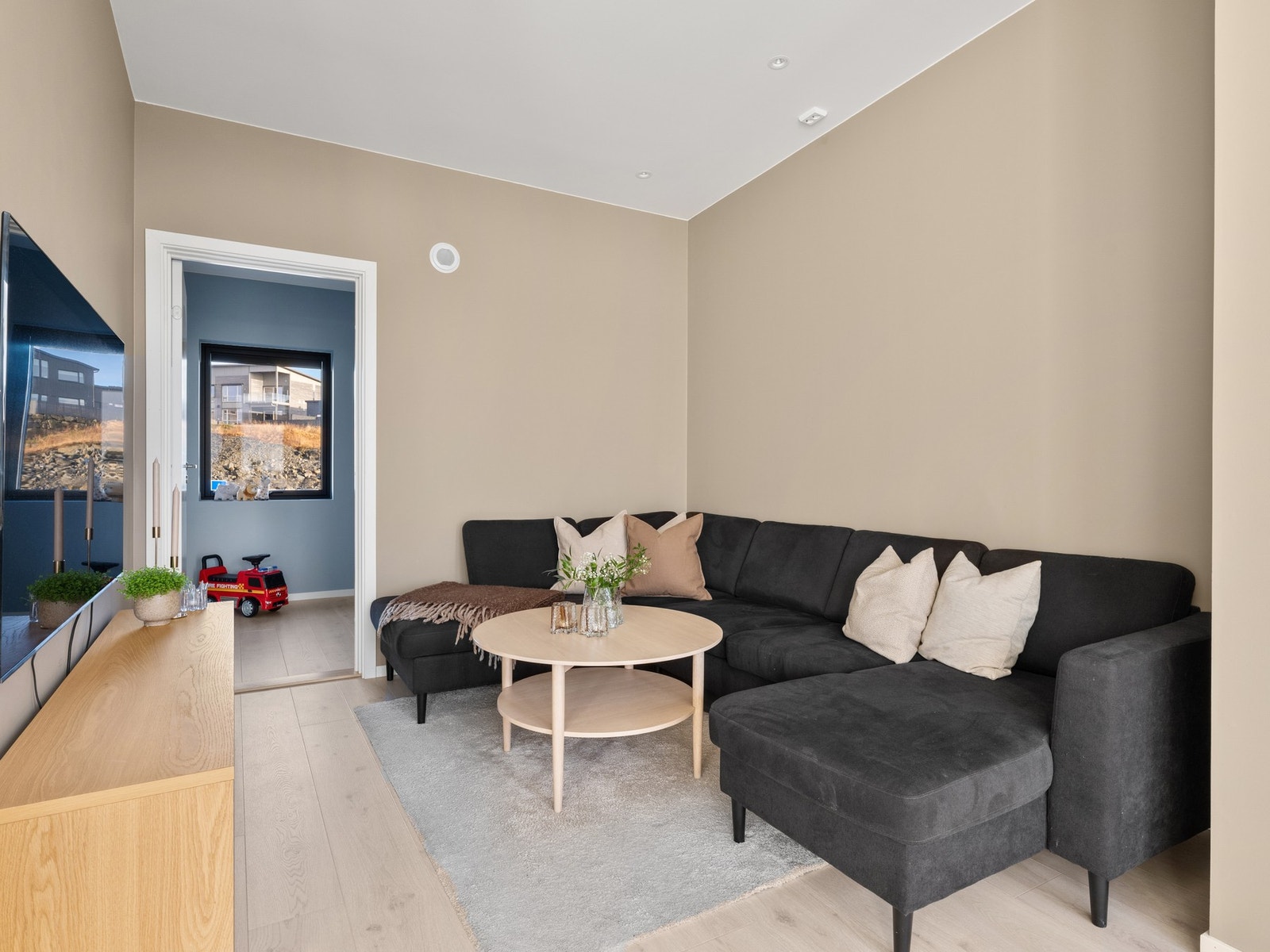 Den åpne løsningen gir plass til både sofa, tv-møblement og spisebord ved kjøkkensonen. Galleribilde