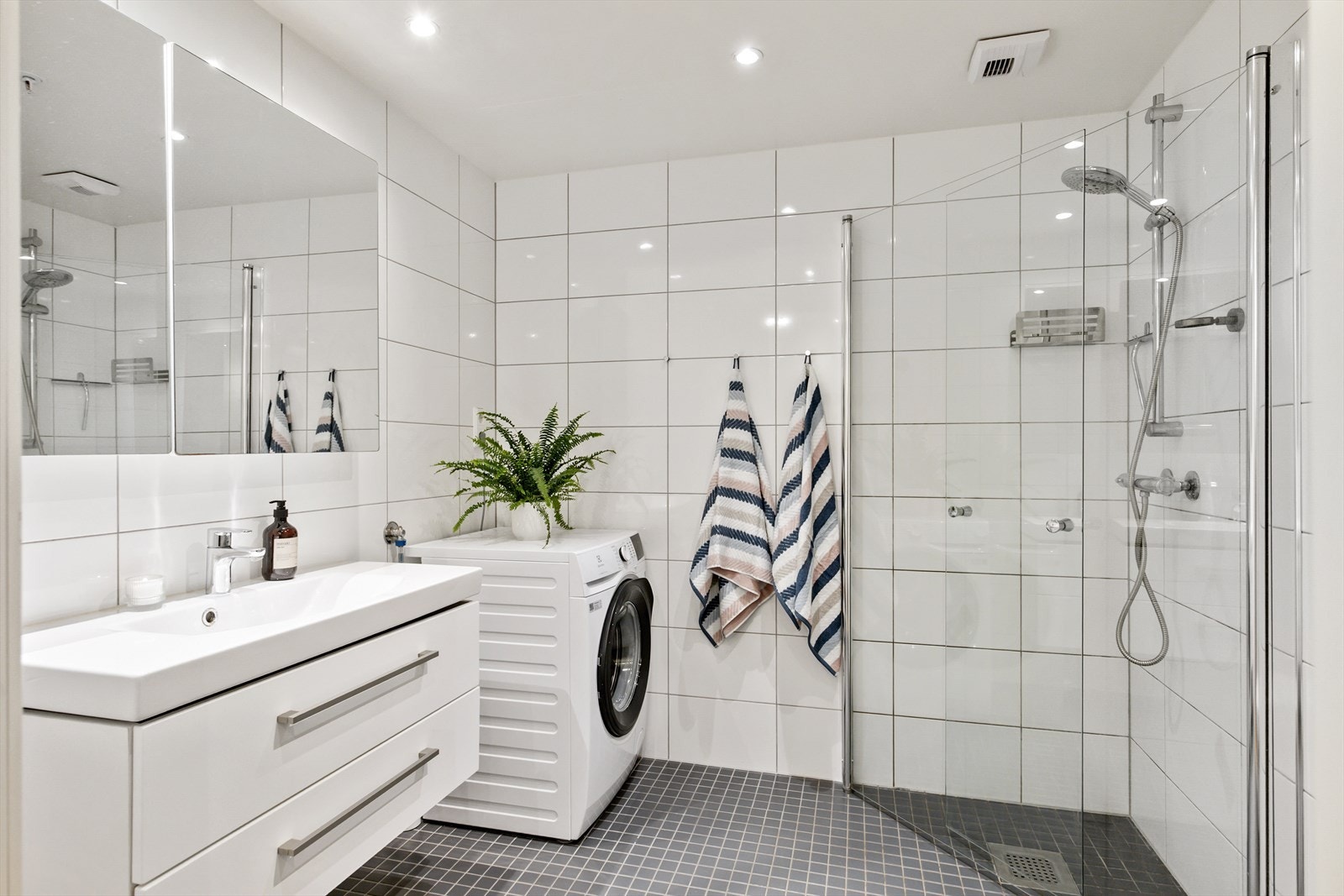 Pent, flislagt baderom med gulvvarme og downlights i himlingen. Det er opplegg vaskemaskin og tørketrommel. Galleribilde