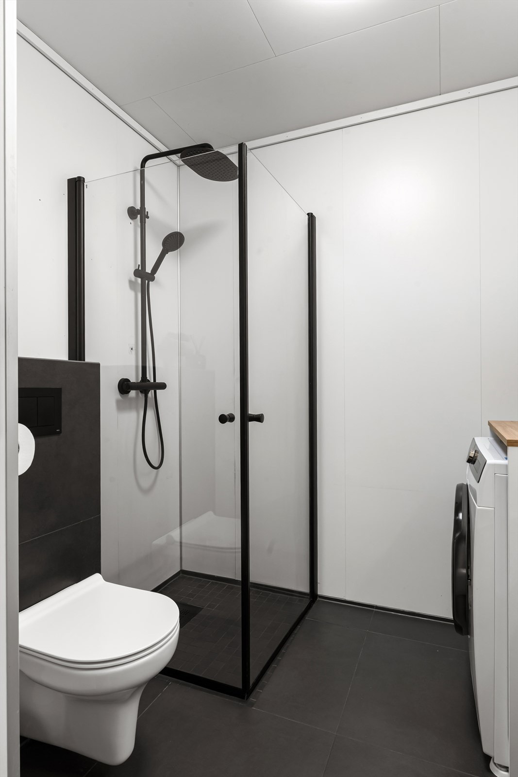 Vegghengt toalett og dusjhjørne med sorte detaljer. Galleribilde