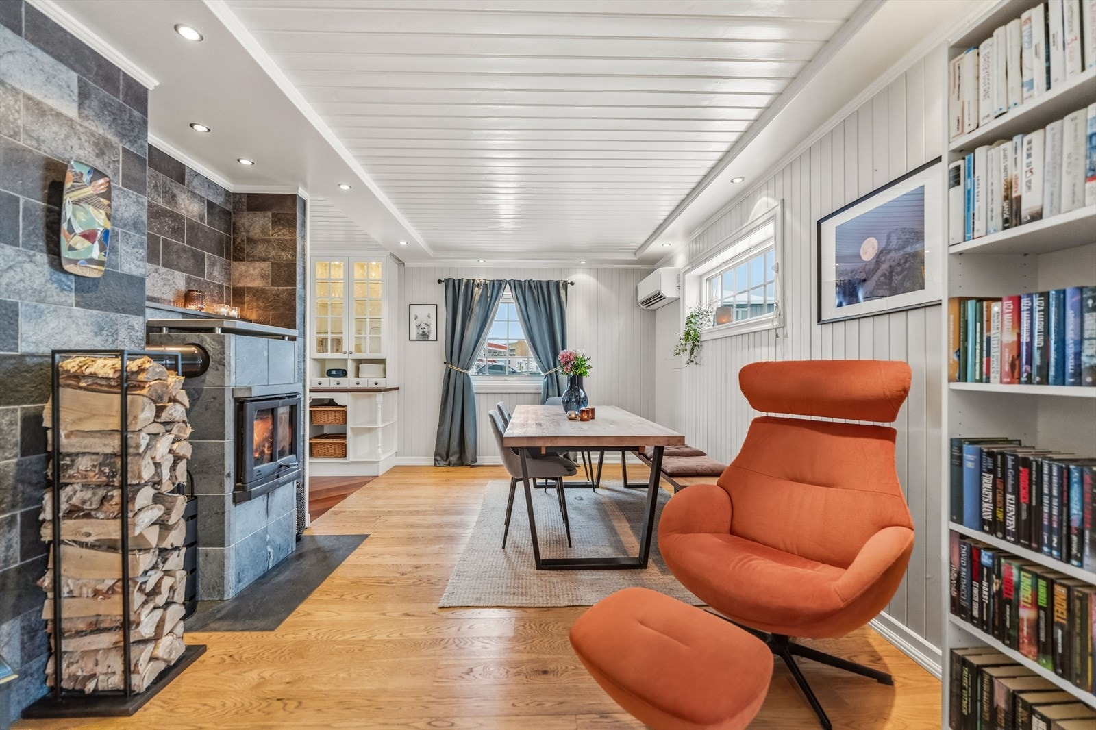 Pipemuren er kledd med grå fliser, og rommet har en sentralt plassert klebersteinsovn. Galleribilde