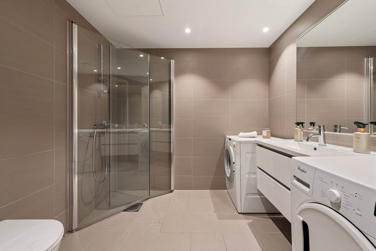 Flislagt og delikat baderom med gulvvarme og downlights som gir ekstra komfort. I tillegg er det opplegg for vaskemaskin. Galleribilde