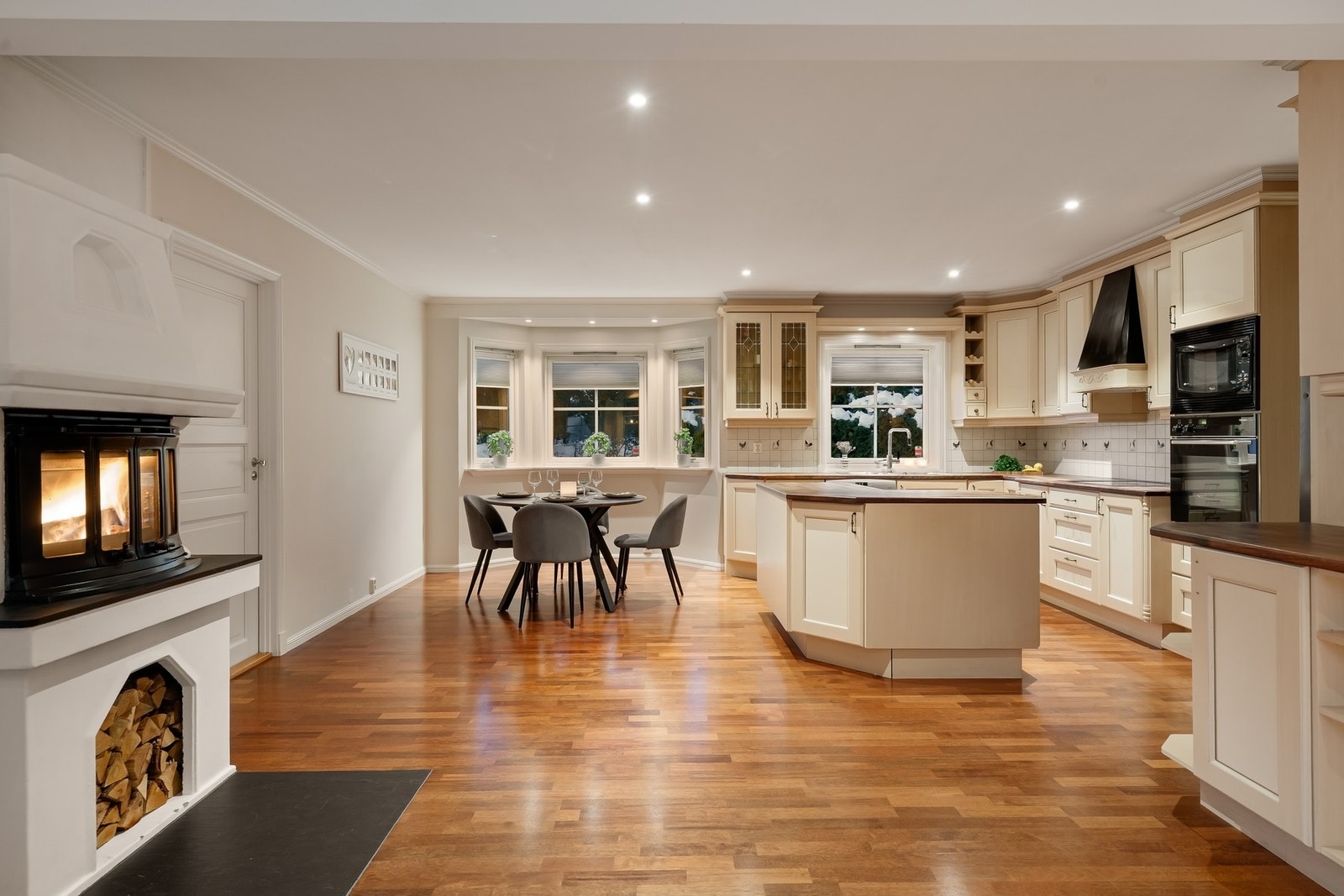 Stort og innholdsrikt kjøkken med plass til en spisegruppe ved kjøkkenvinduet. Peisen lager ekstra god stemning. Galleribilde