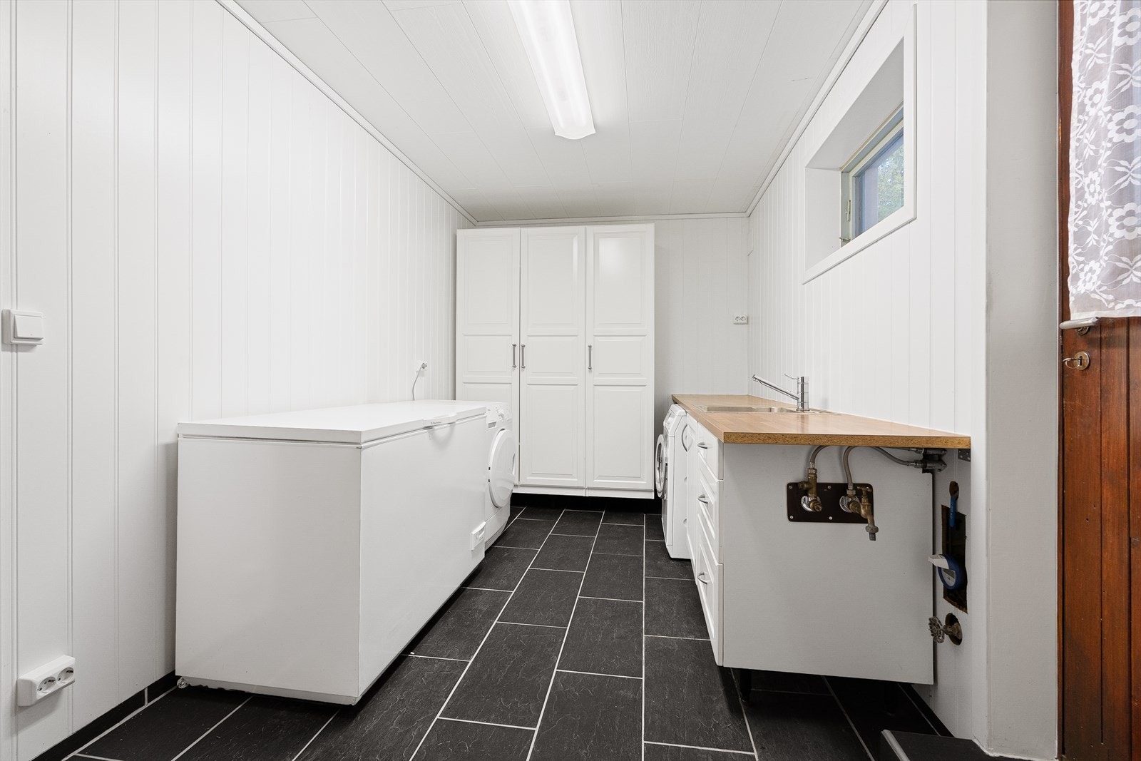 Praktisk vaskerom med utgang. Her er det satt inn godt med skaper som gir gode oppbevaringsmuligheter. Galleribilde