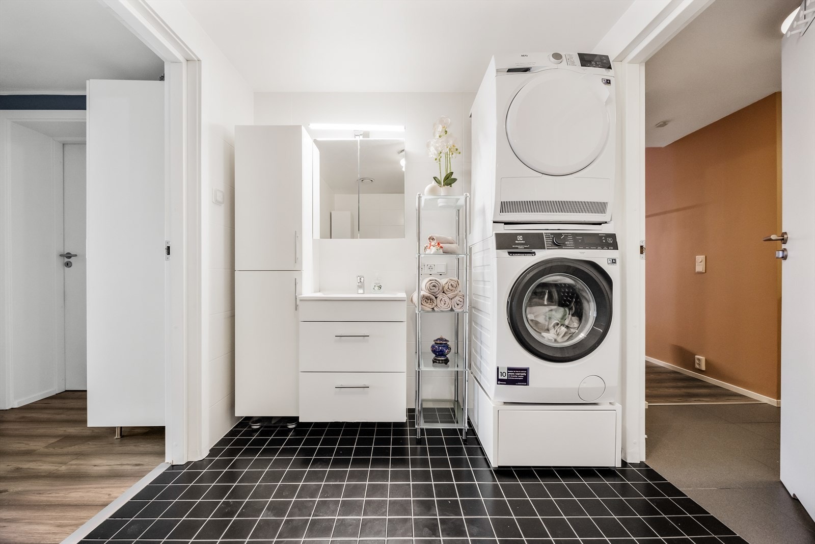 Badet er innredet med servant i baderomsinnredning, vegghengt skap, dusjhjørne, toalett og opplegg for vaskemaskin og tørketrommel. Galleribilde