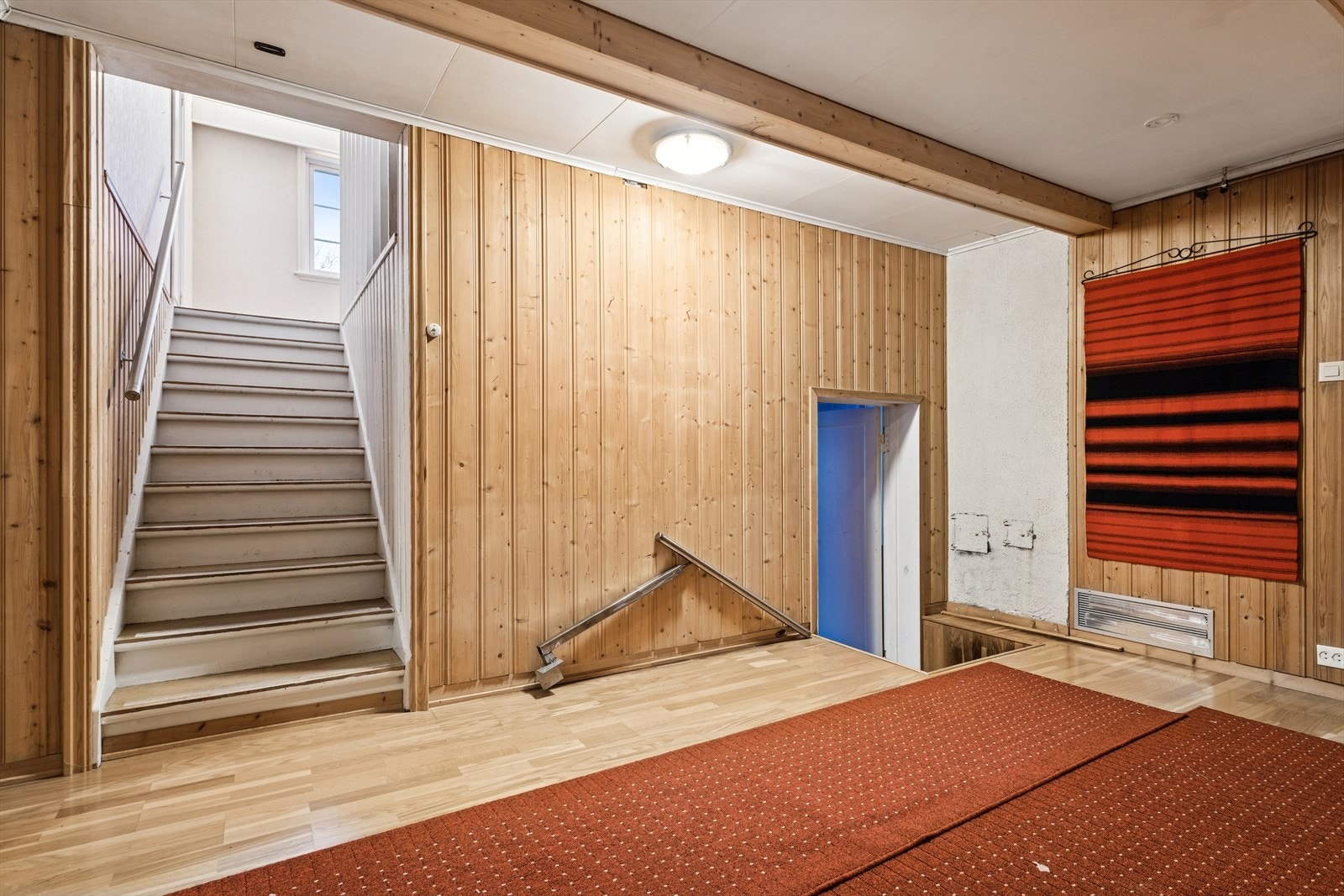 Trepanel på veggene gir en varm følelse, mens laminatgulvet gir et praktisk underlag. Det er montert håndlist på den ene siden i trappen. Galleribilde