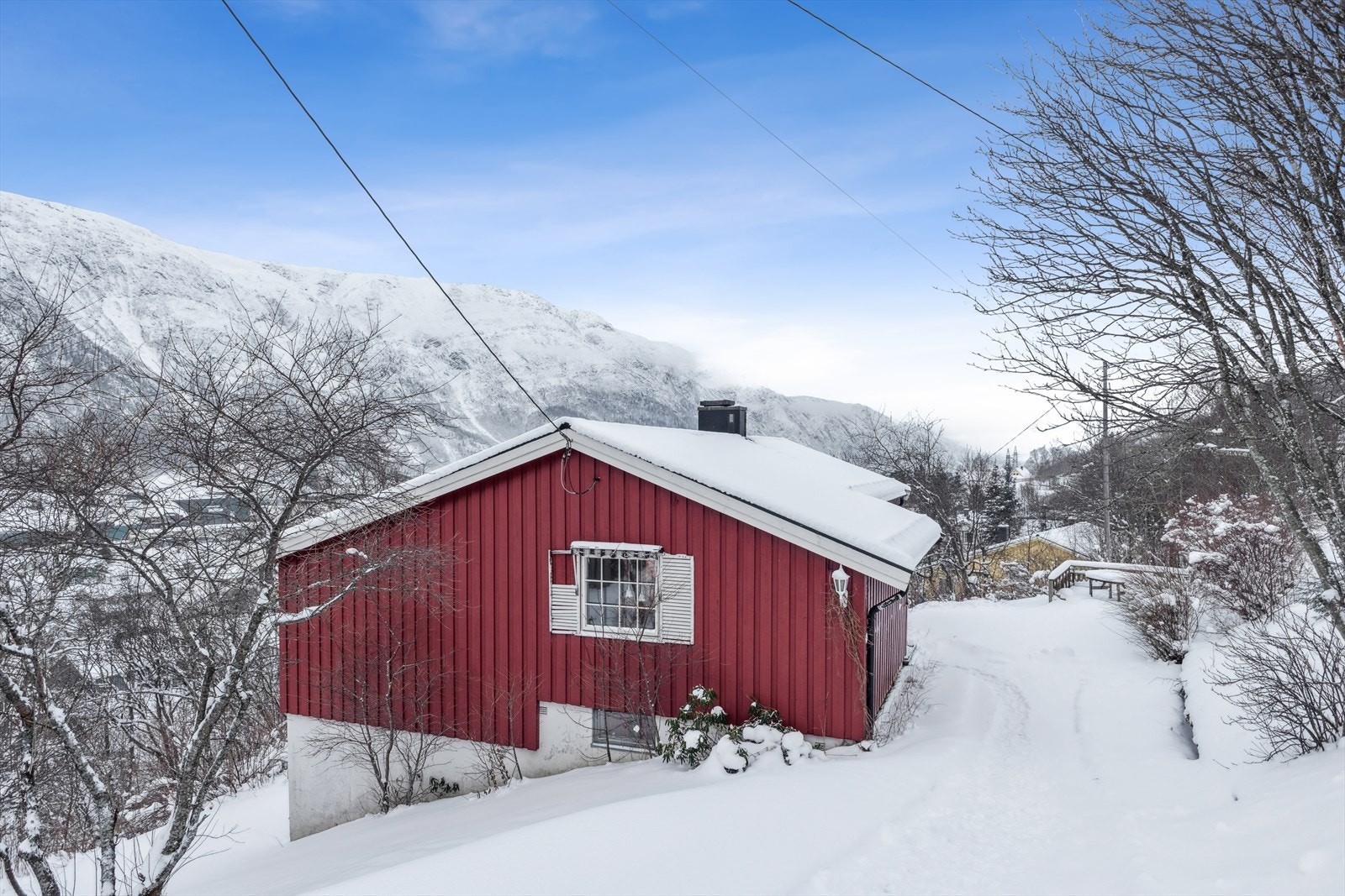 Boligen har skrånende tomt med gruset gårdsvei som gir adkomst til eiendommen. Tomten gir også plass til bilparkering. Galleribilde