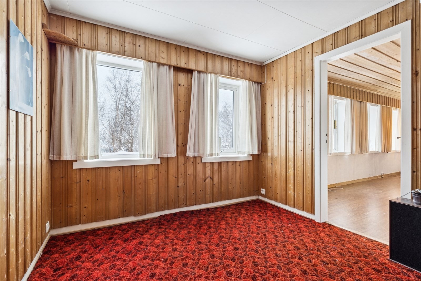 Vegger med trepanel gir et tradisjonelt preg, mens store vinduer slipper inn naturlig lys. Rommet har teppebelagt gulv. Galleribilde