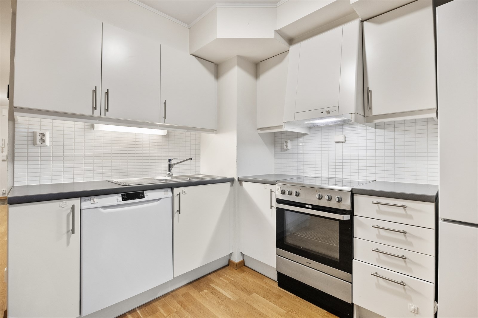 Kjøkkeninnredningen har hvite, glatte fronter og en slitesterk laminatbenkeplate. Galleribilde